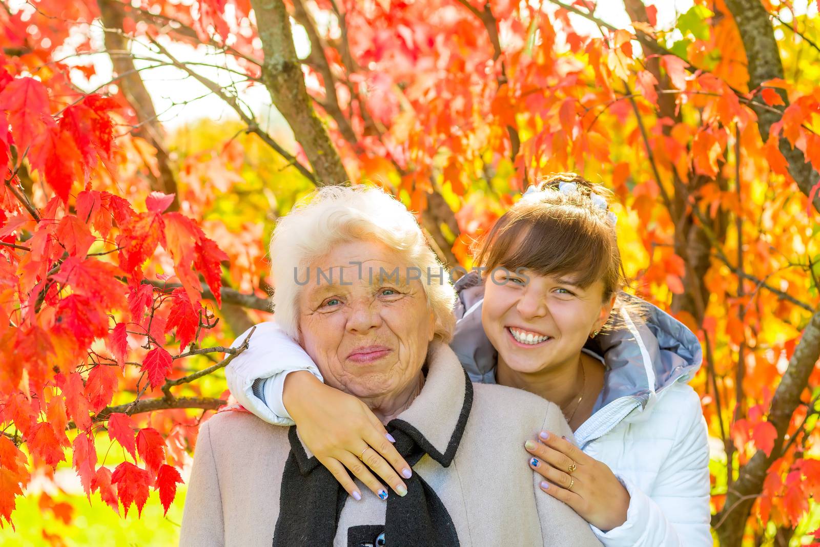 girl hugging her old grandmother in autumn park