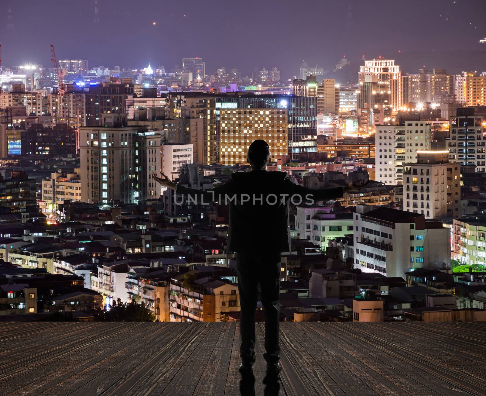 Silhouette of businessman open arms against city with copyspace.