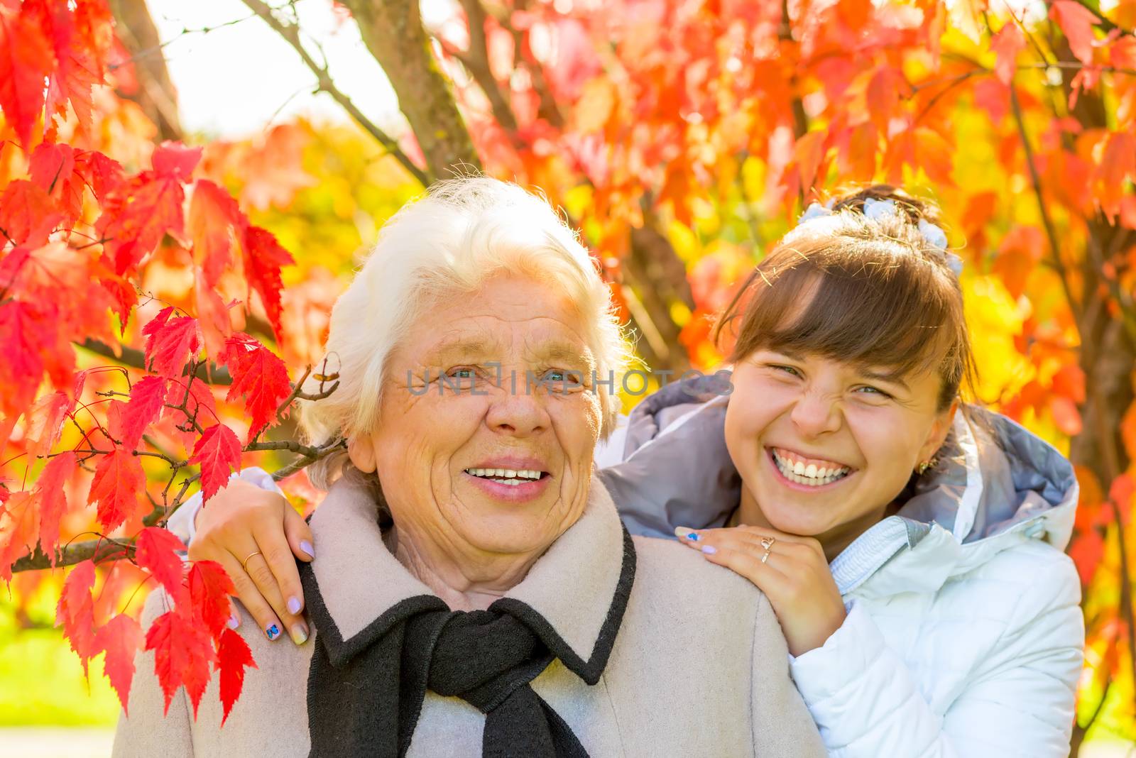 laughing grandmother and granddaughter in the park with beautiful red leaves