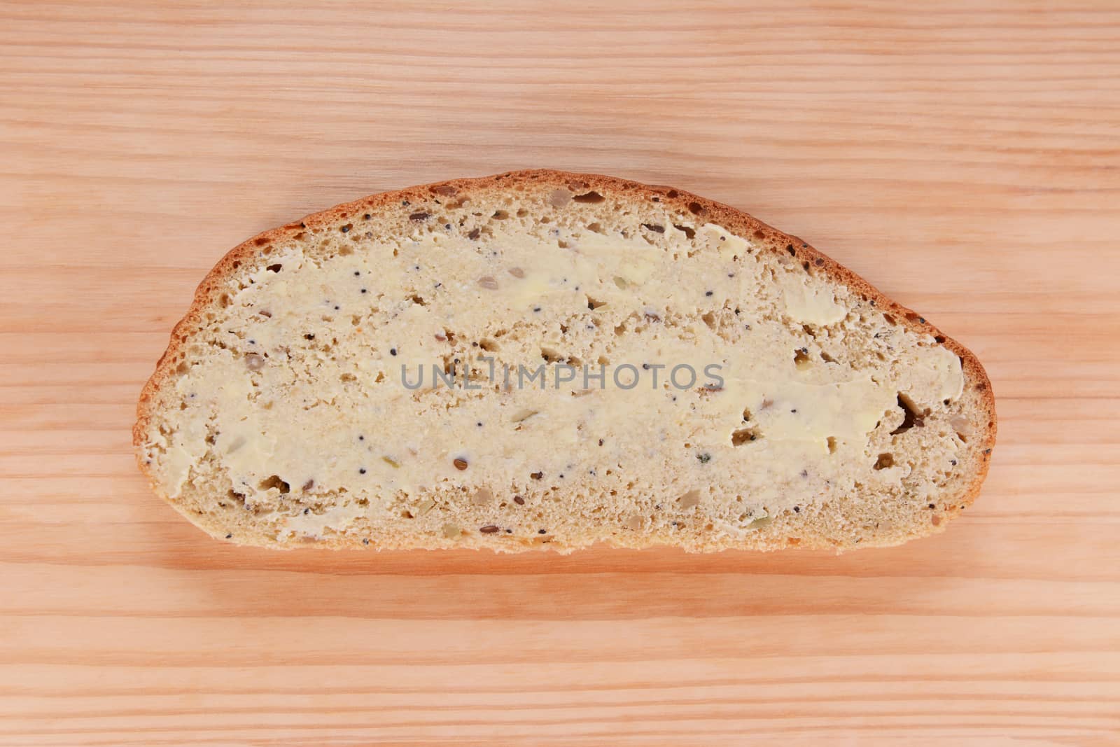 Slice of buttered freshly baked bread on a wooden table