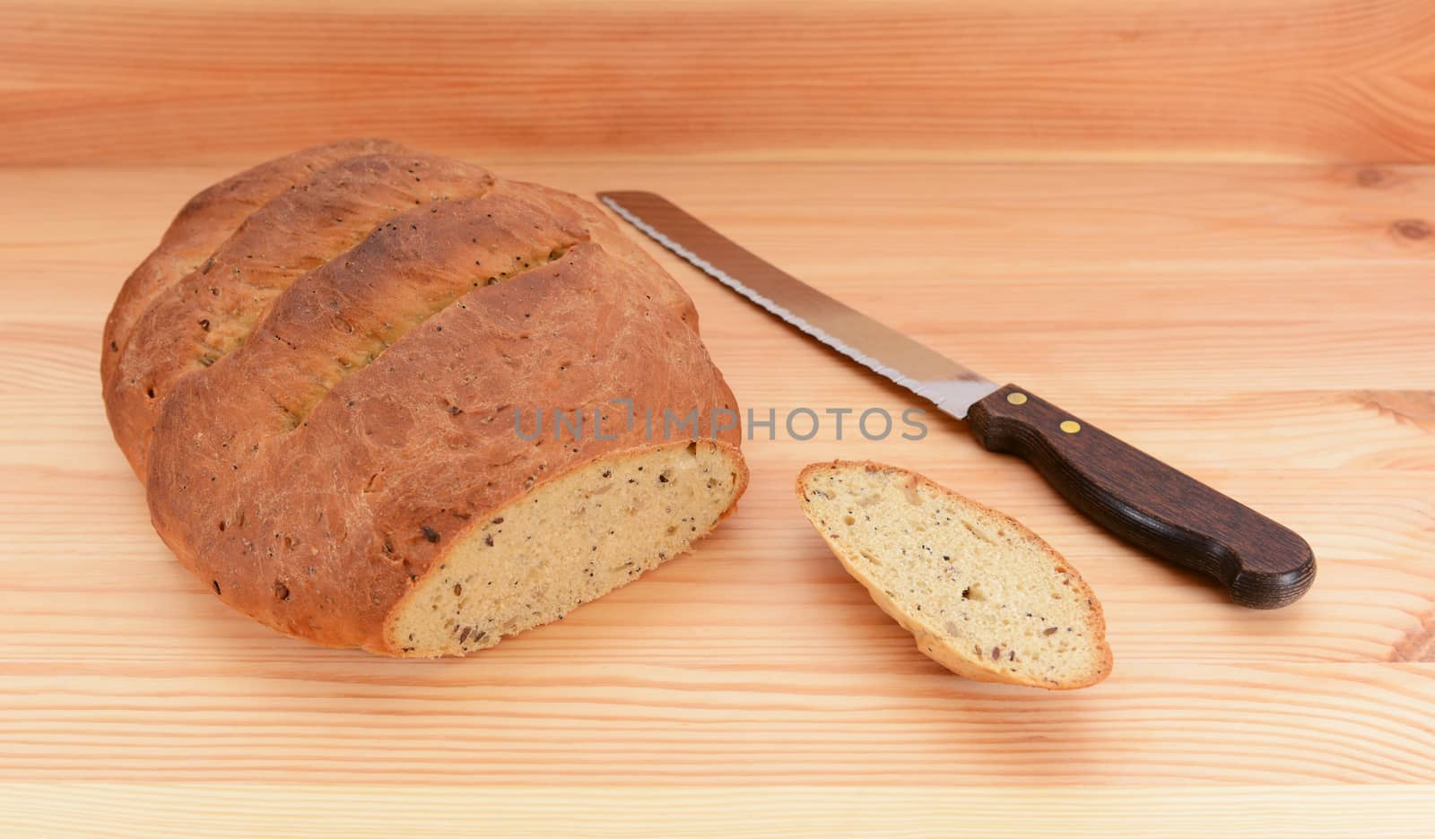 Freshly baked loaf of bread with the first slice taken and a bread knife on the table