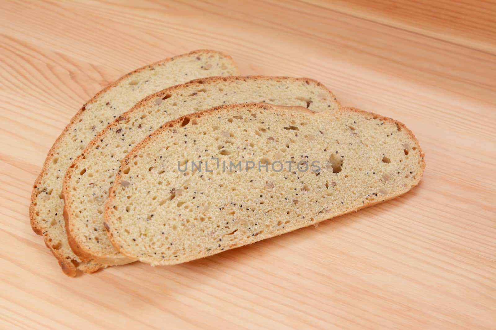 Three slices of multi seed malted bread on a pine wood table
