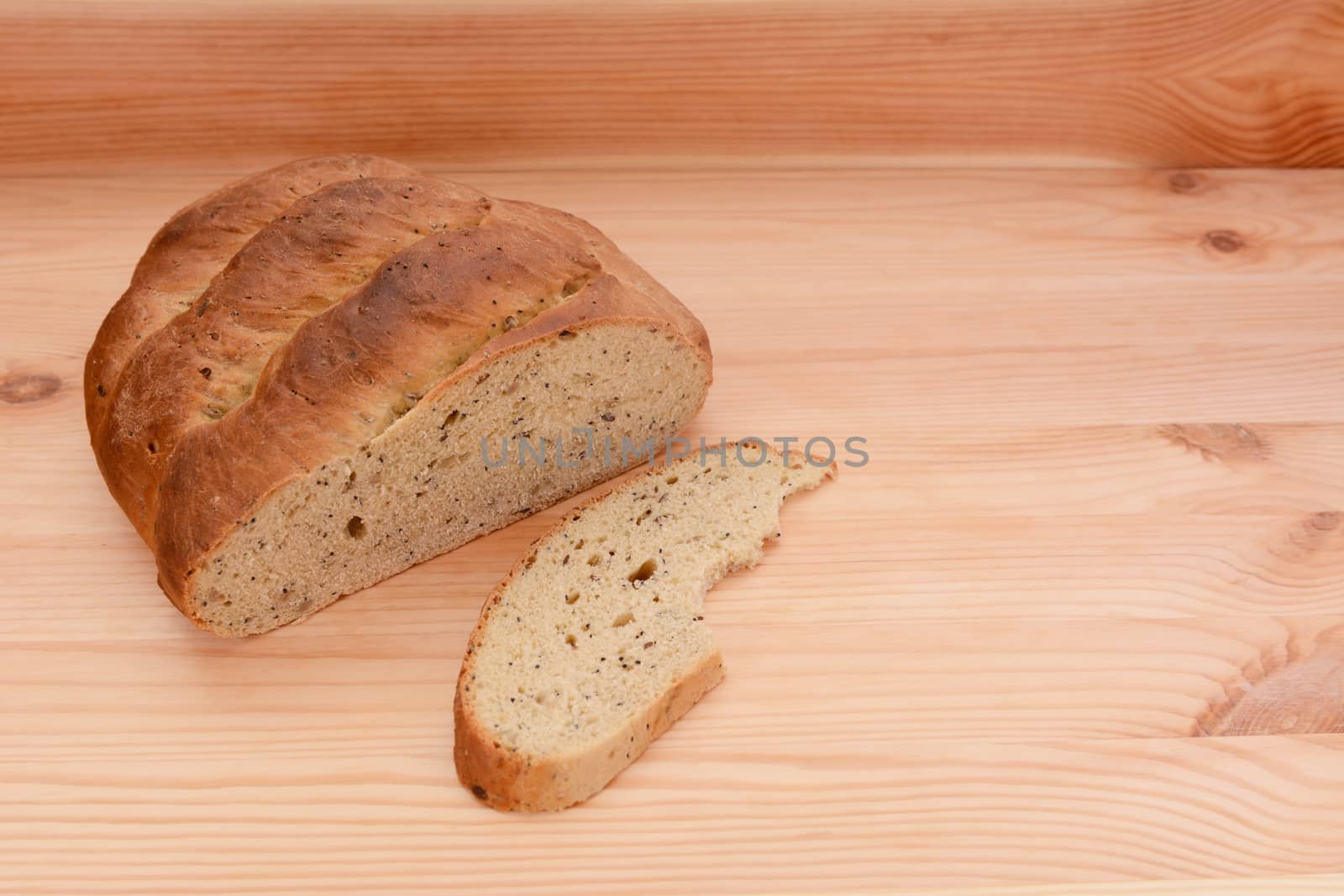 Half-eaten loaf of bread on a wooden table with a cut slice with a bite taken from it
