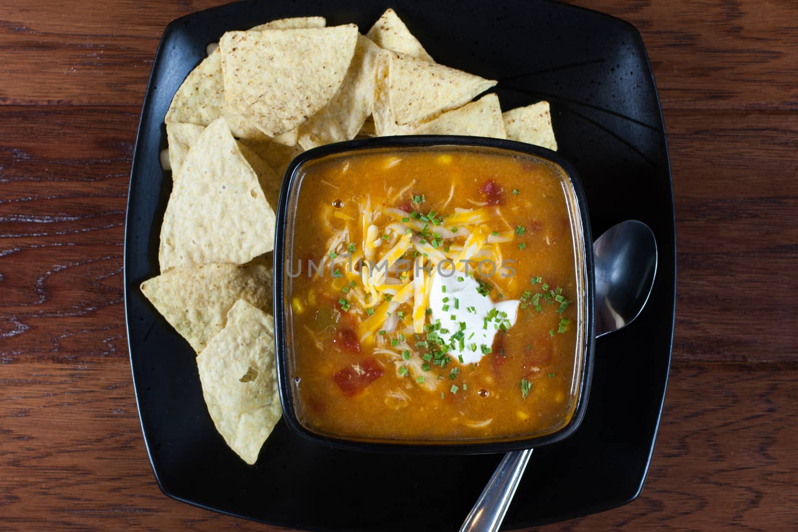 A bowl of chicken enchilada soup with white corn tortillas on the side.