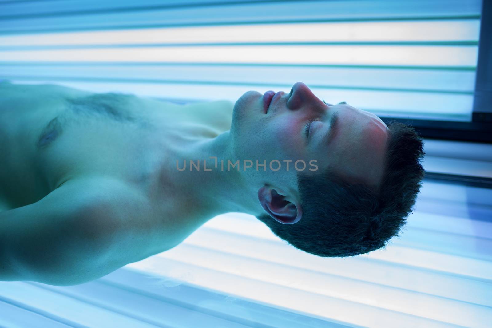 Handsome young man relaxing during a tanning session by viktor_cap