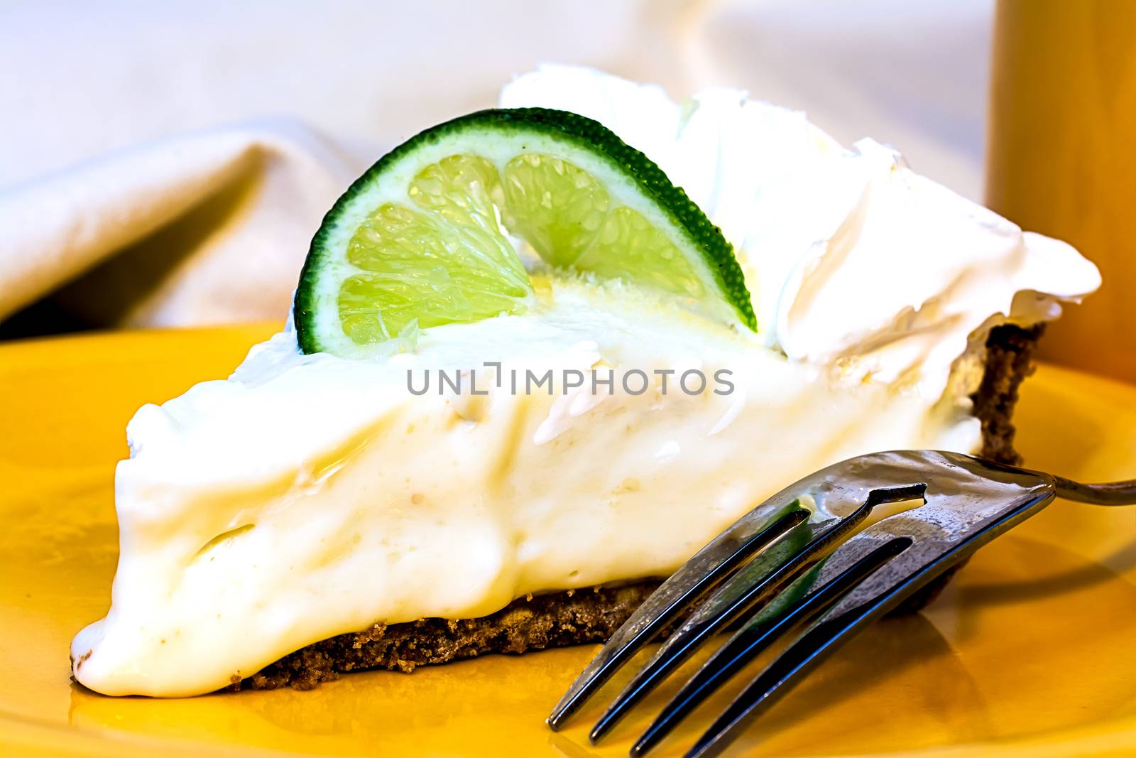 Key lime pie closeup with fork on plate.
