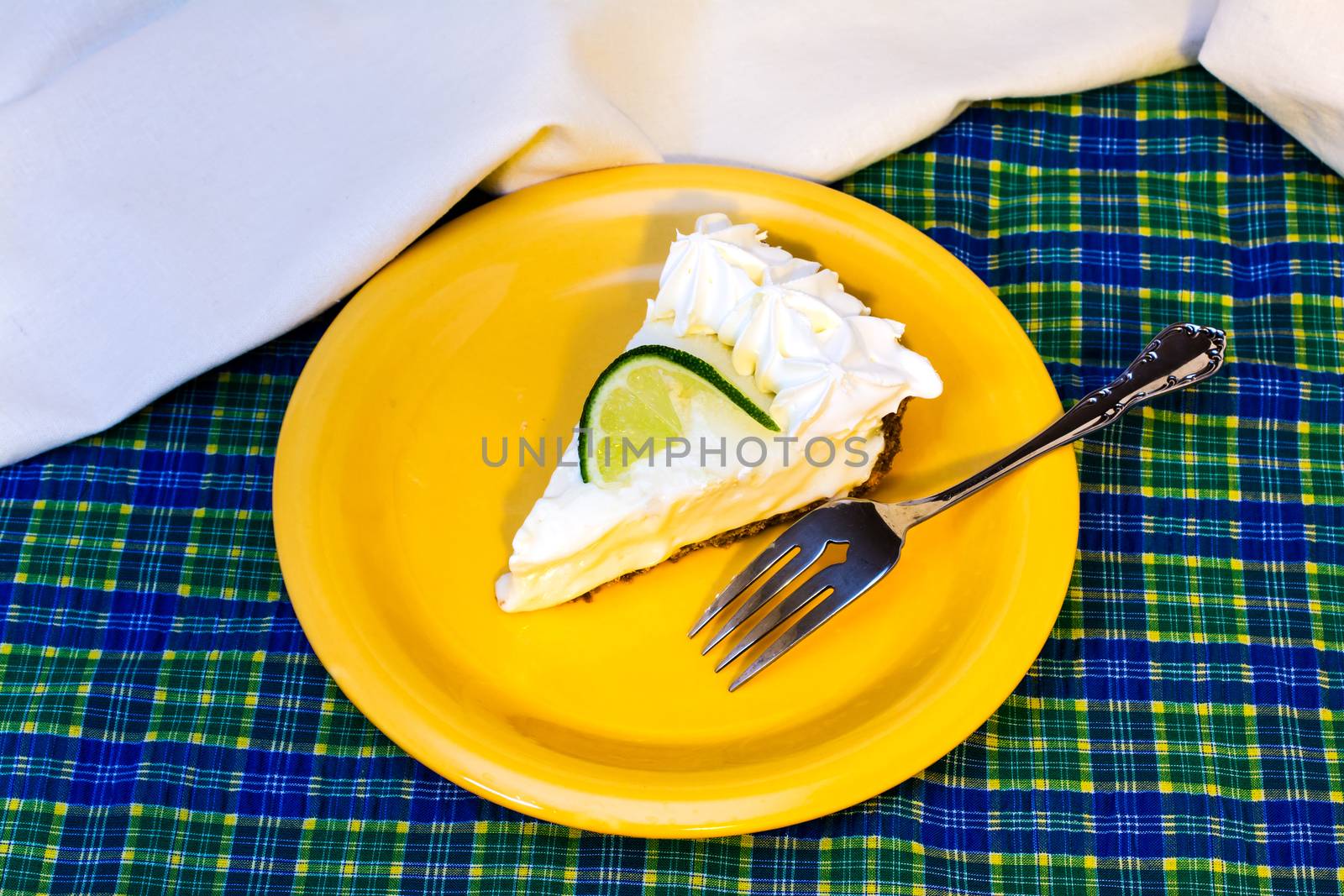 Slice of key lime pie with fork overhead.