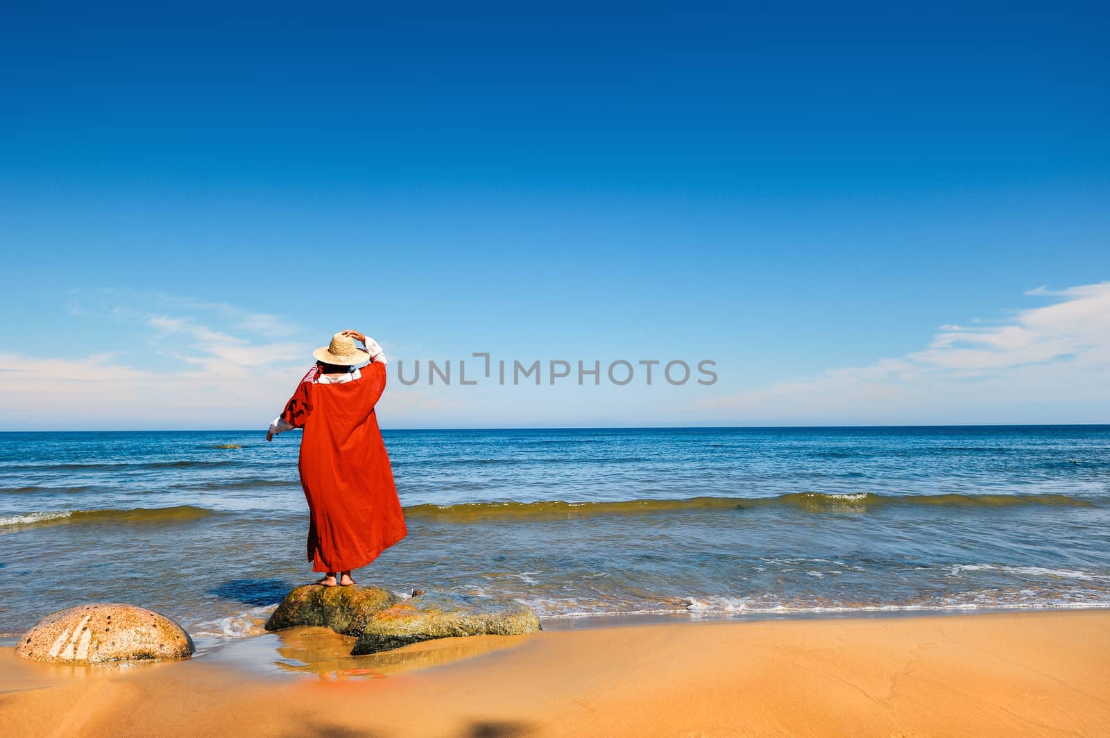 Woman in red dress on the seashore