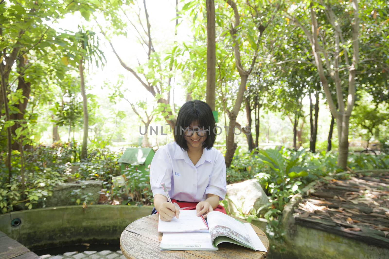 Girl reading and homework. At a table in the park There are some shady trees planted