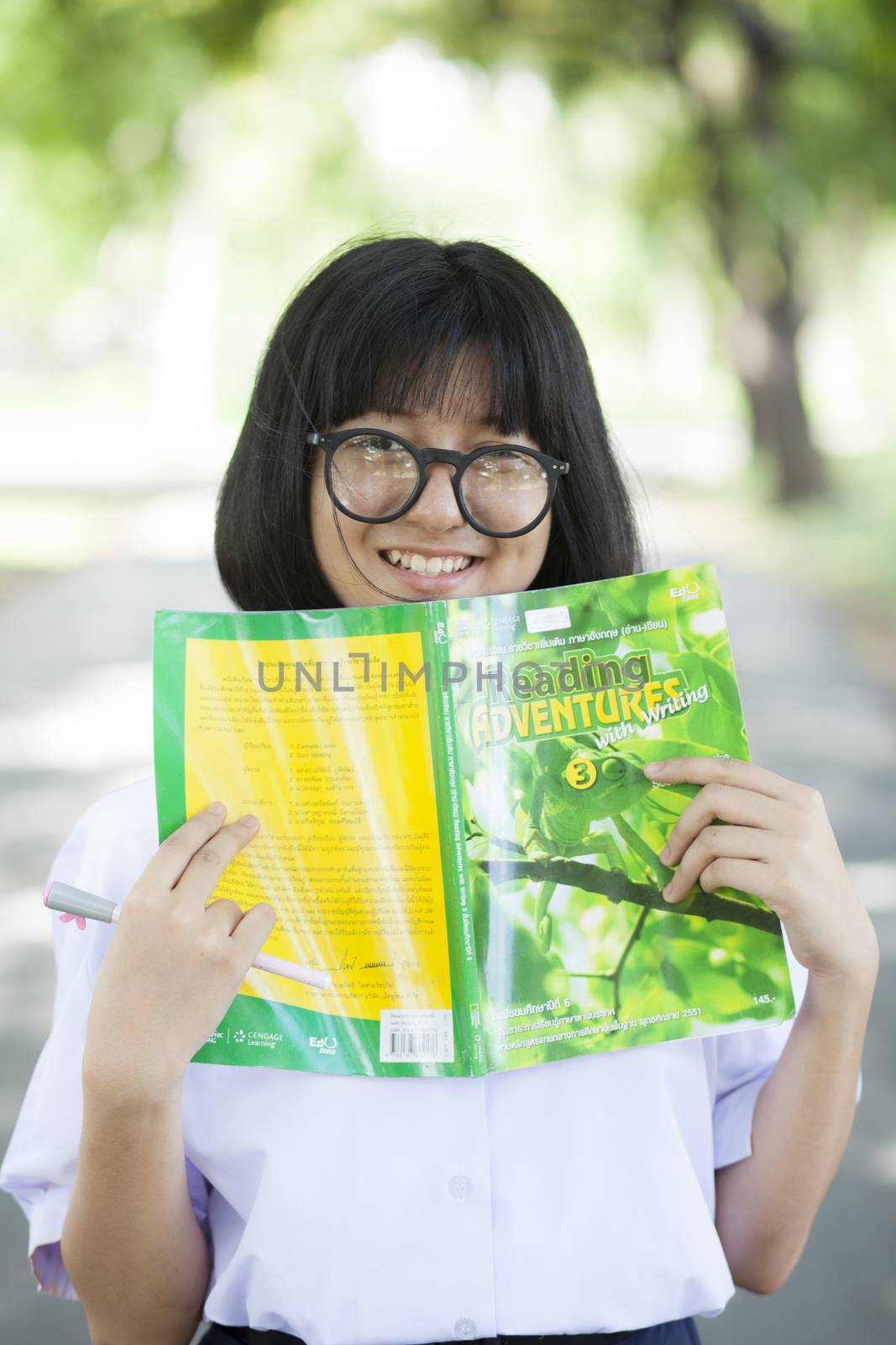 Young woman holding yellow book. Smiling and relaxing in the garden.