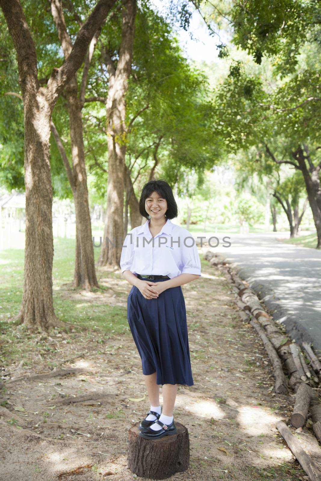 Girl smiling And standing on a piece of wood in the park.