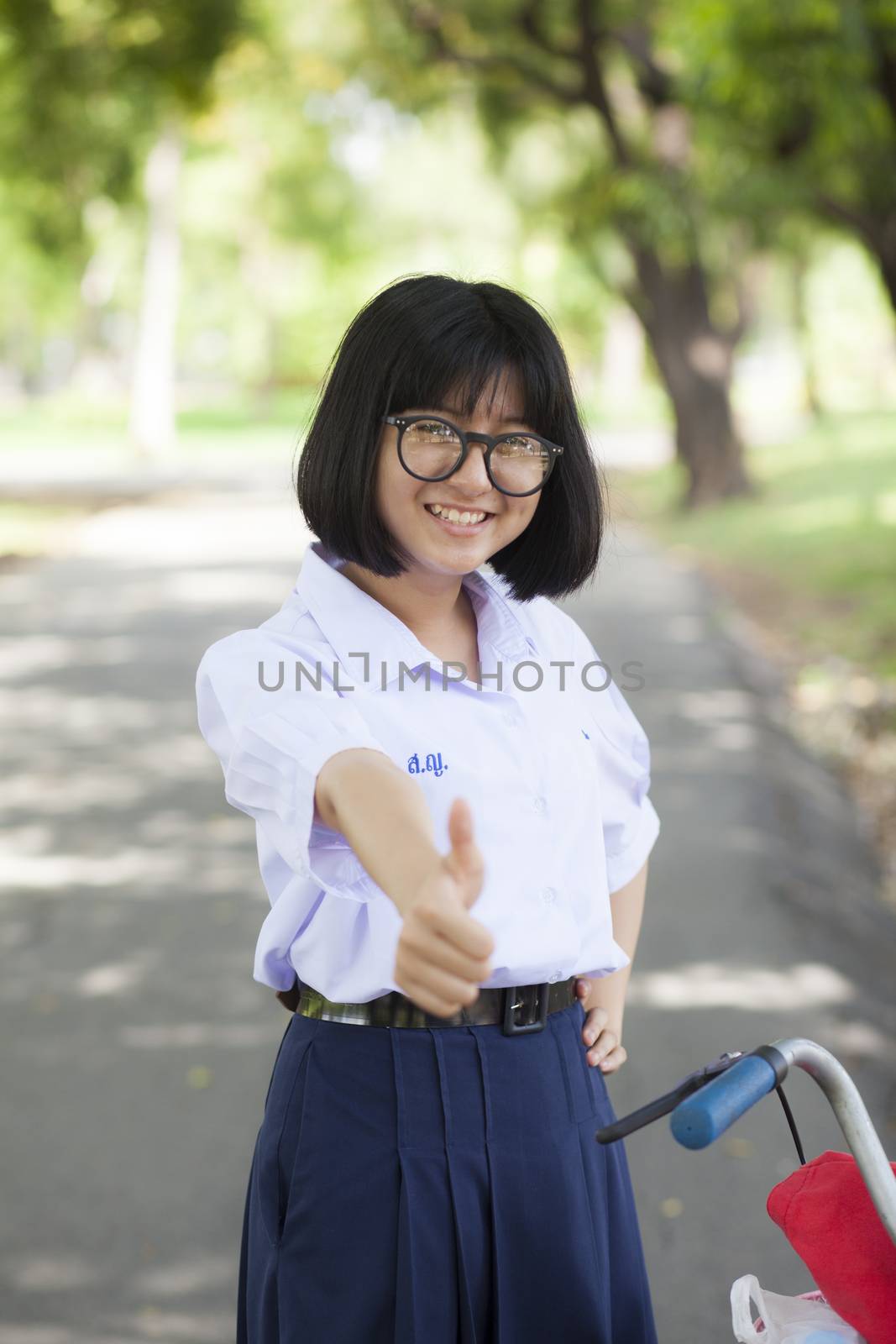 girl smile and relax Standing on the walkway in the park. There is a shady tree