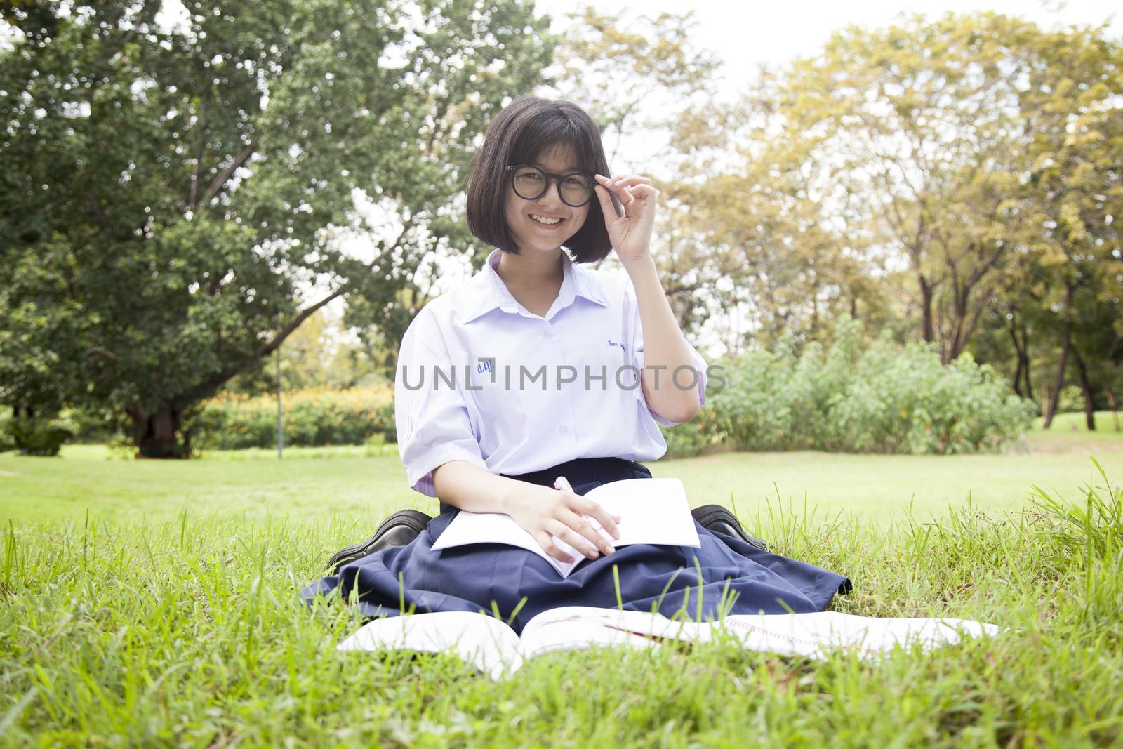 Schoolgirl was reading on the lawn. Smiling and happy within the park.