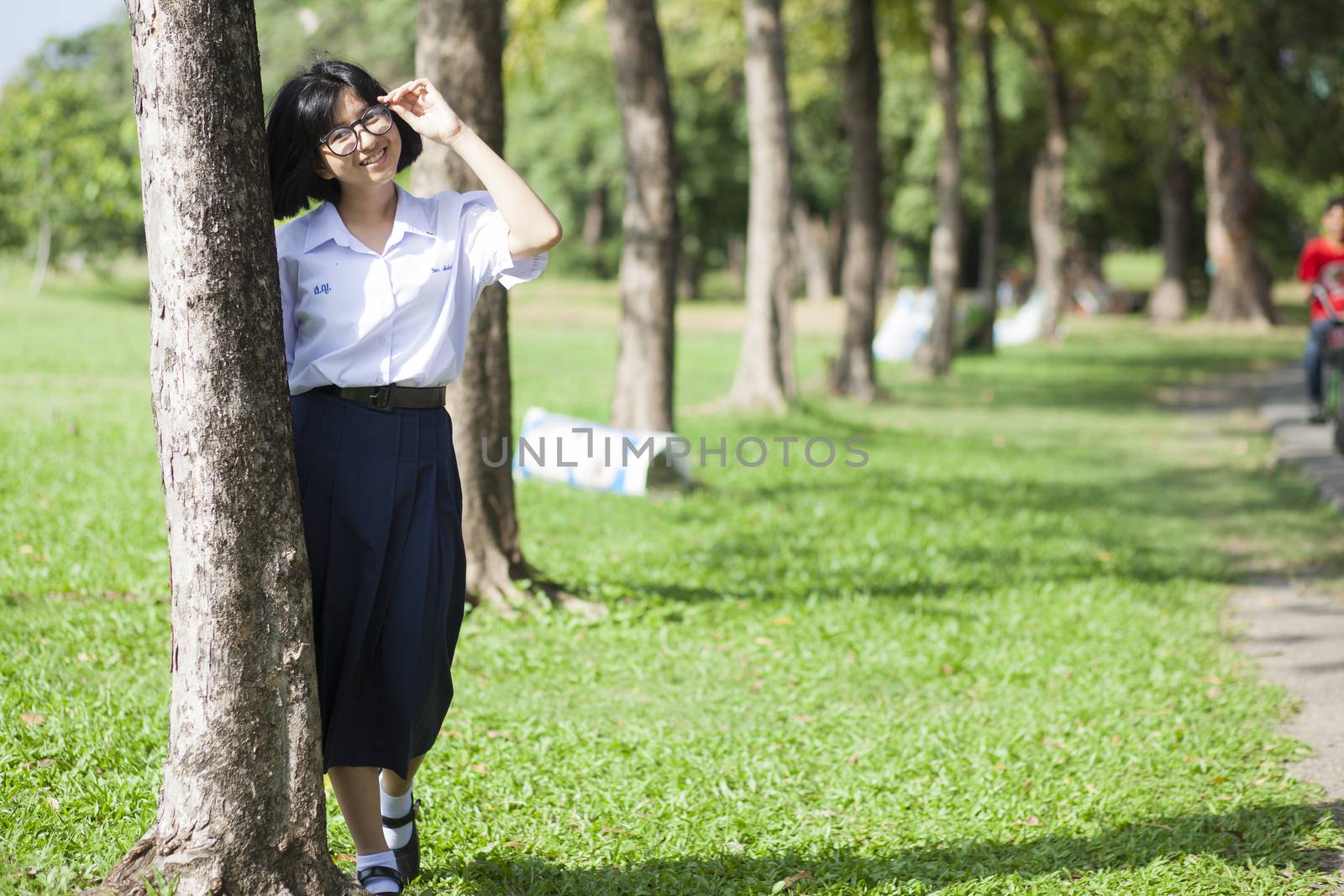 Girl standing and smiling near a tree. by a454