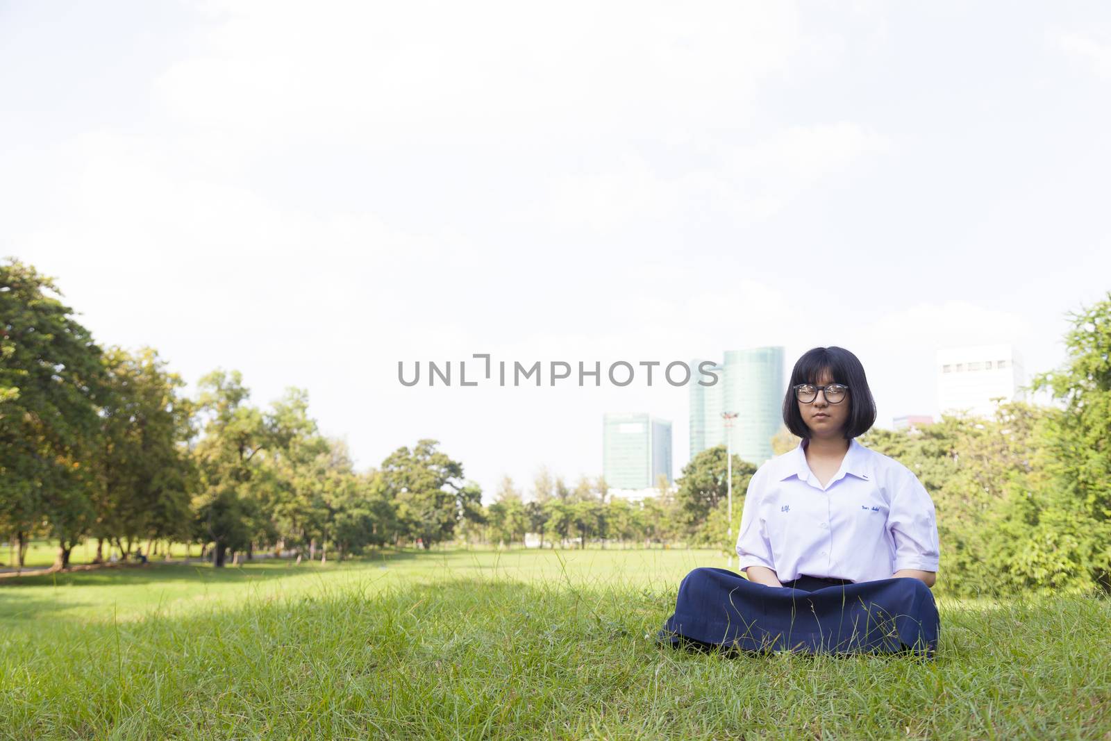 girl was meditating On the grass in the park. Girl wear glasses