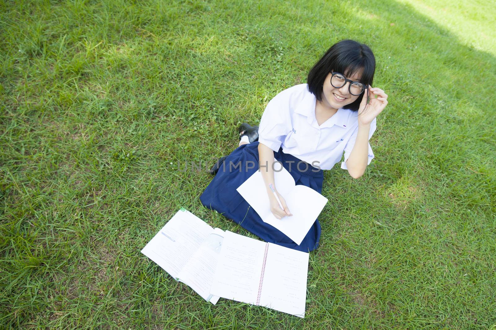 Girl reading on the lawn. Smiling a happy and enjoy. In a shady park