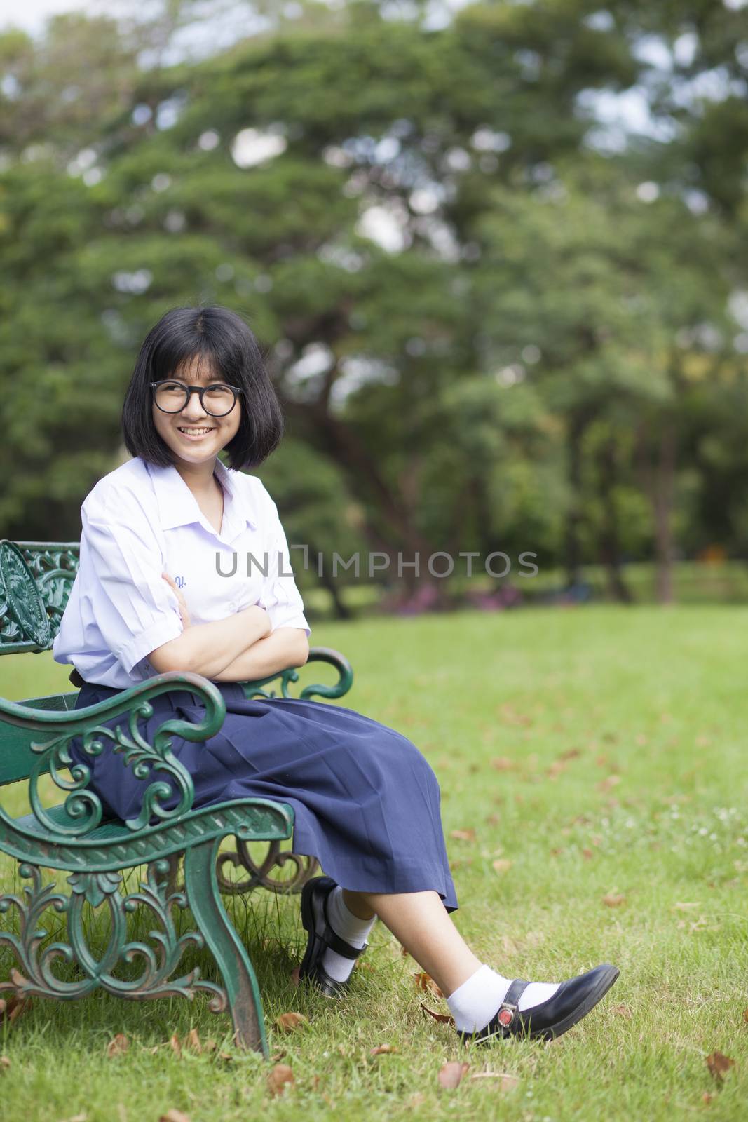 Girl smile and sitting on the bench. Look happy and relaxed. In a shady park.