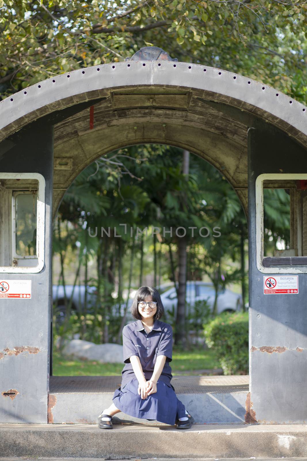 Girl wearing glasses smiling. Sitting on ground in the park. Holiday happily.