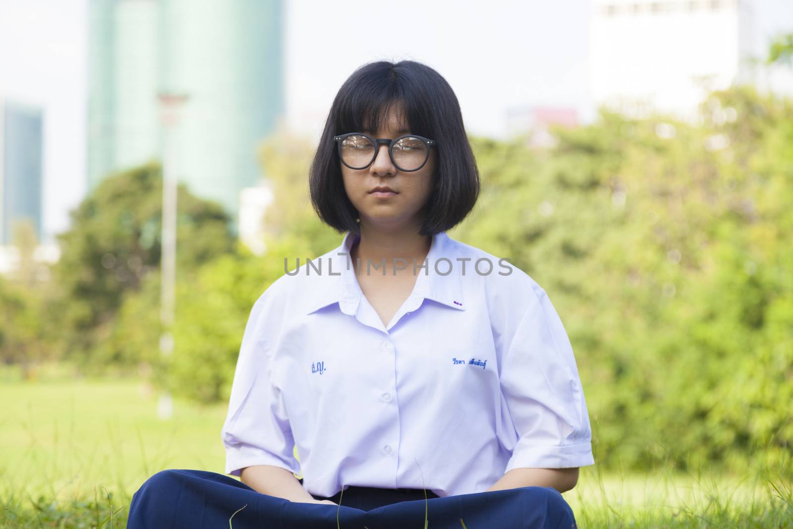 girl was meditating On the grass in the park. Girl wear glasses