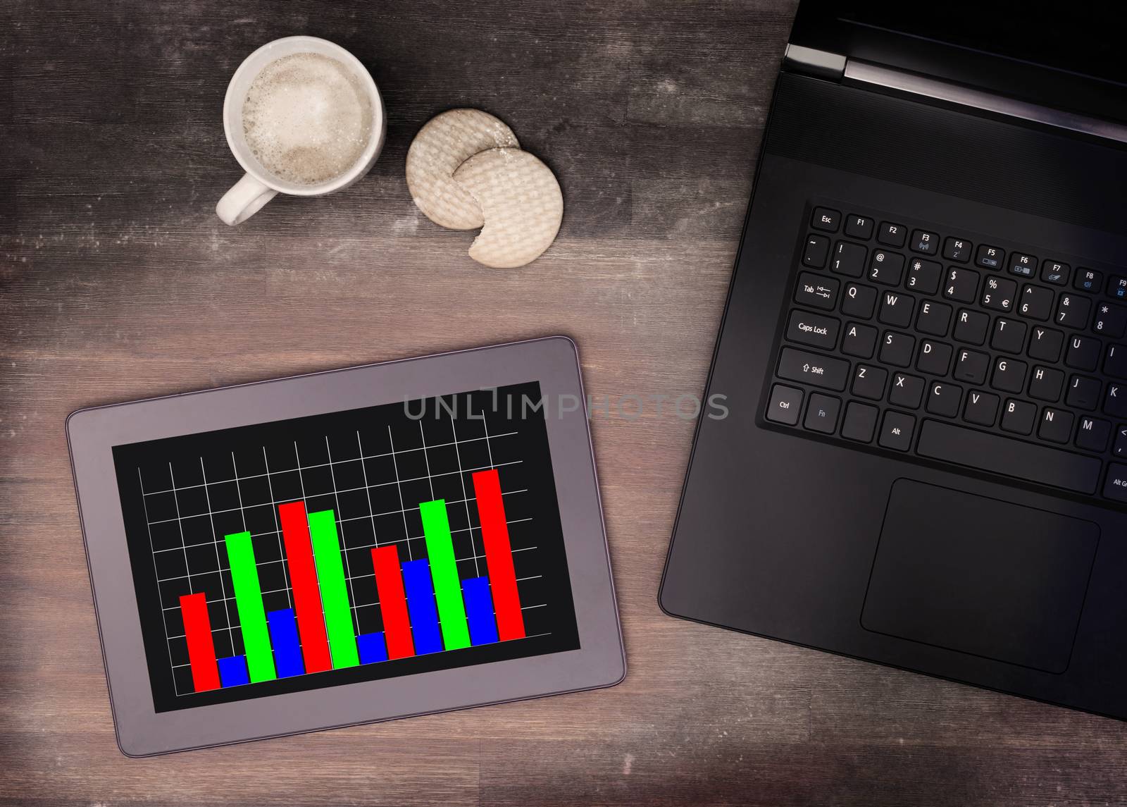 Tablet touch computer gadget on wooden table, graph, vintage look