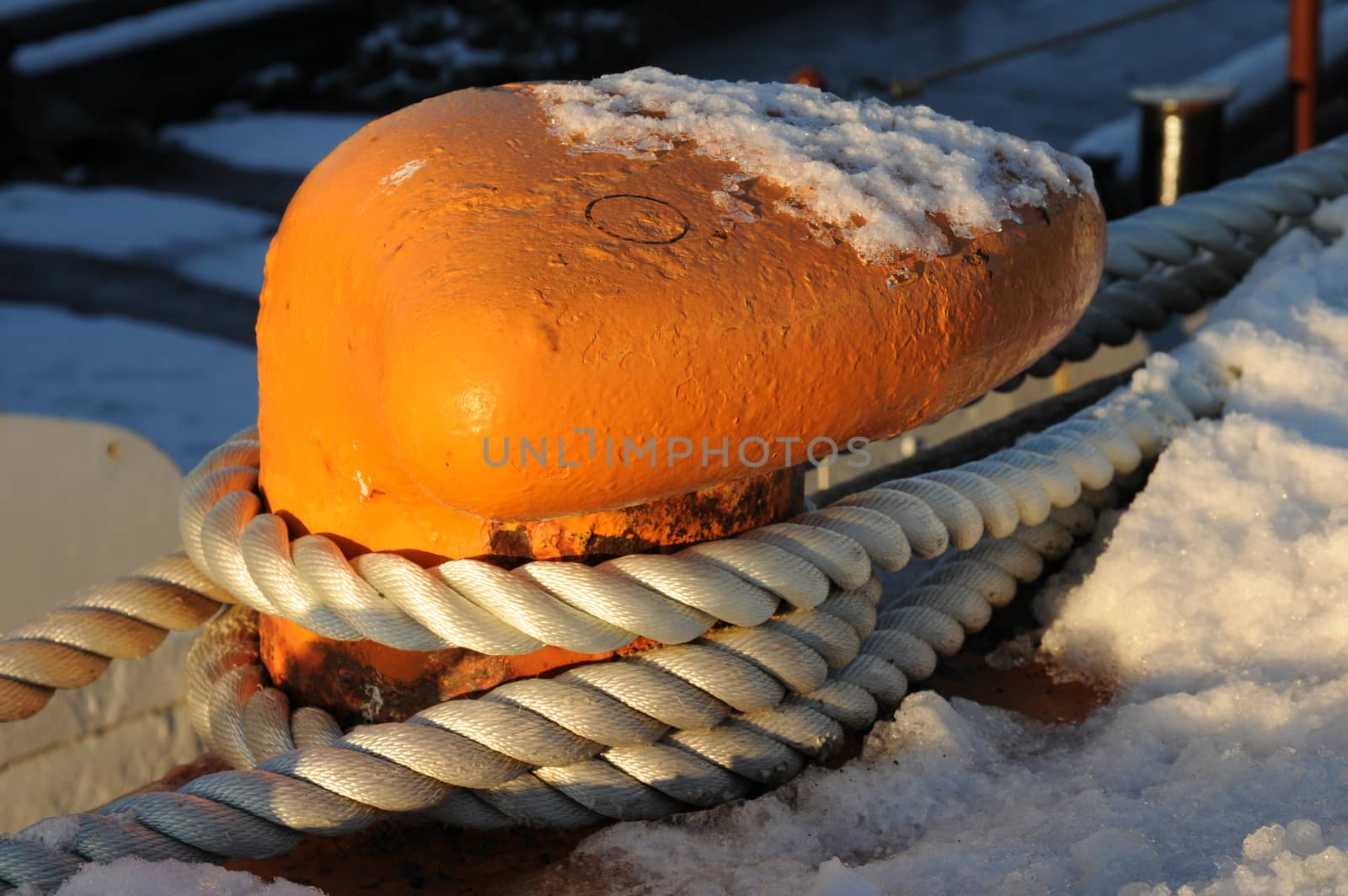 Orange mooring and white rope secure a small ship