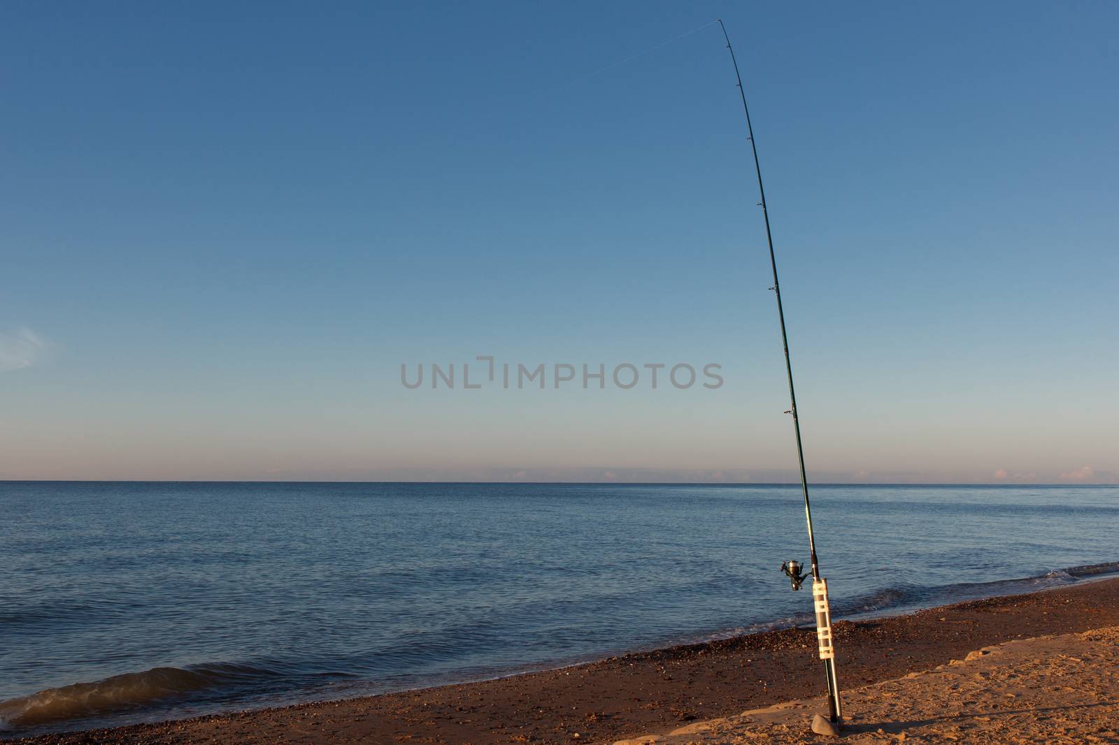 A fishing pole in sand by the sea