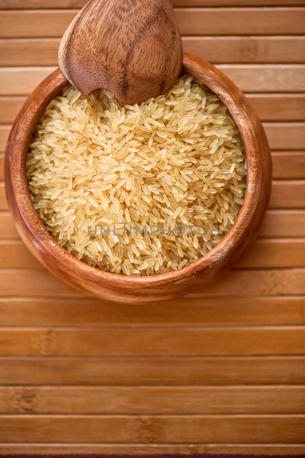 golden rice on wooden plate on wooden background