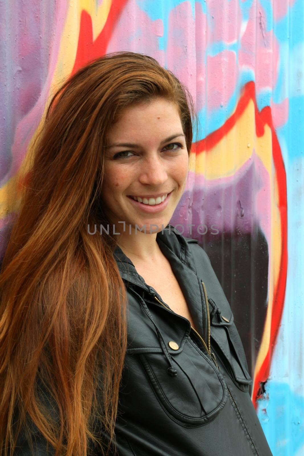 Portrait of a woman with colorful wall in the background.