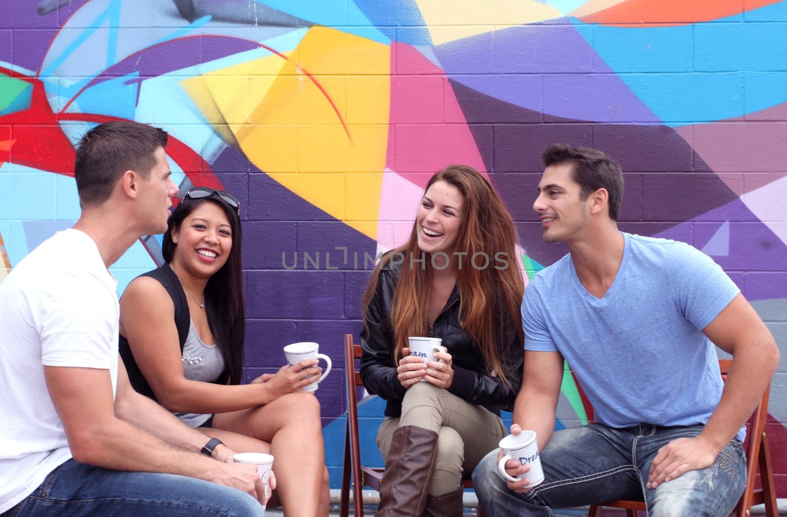 Four friends sitting together during a brake drinking coffee.