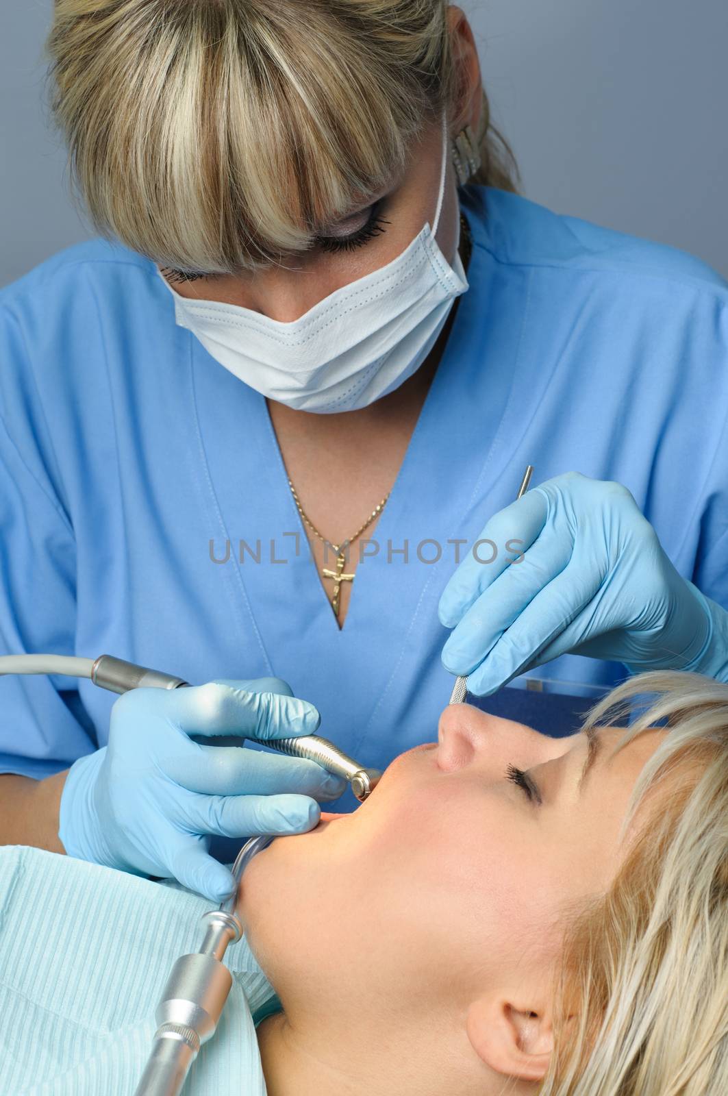 dentist at work with patient, using dental drill to cure the tooth