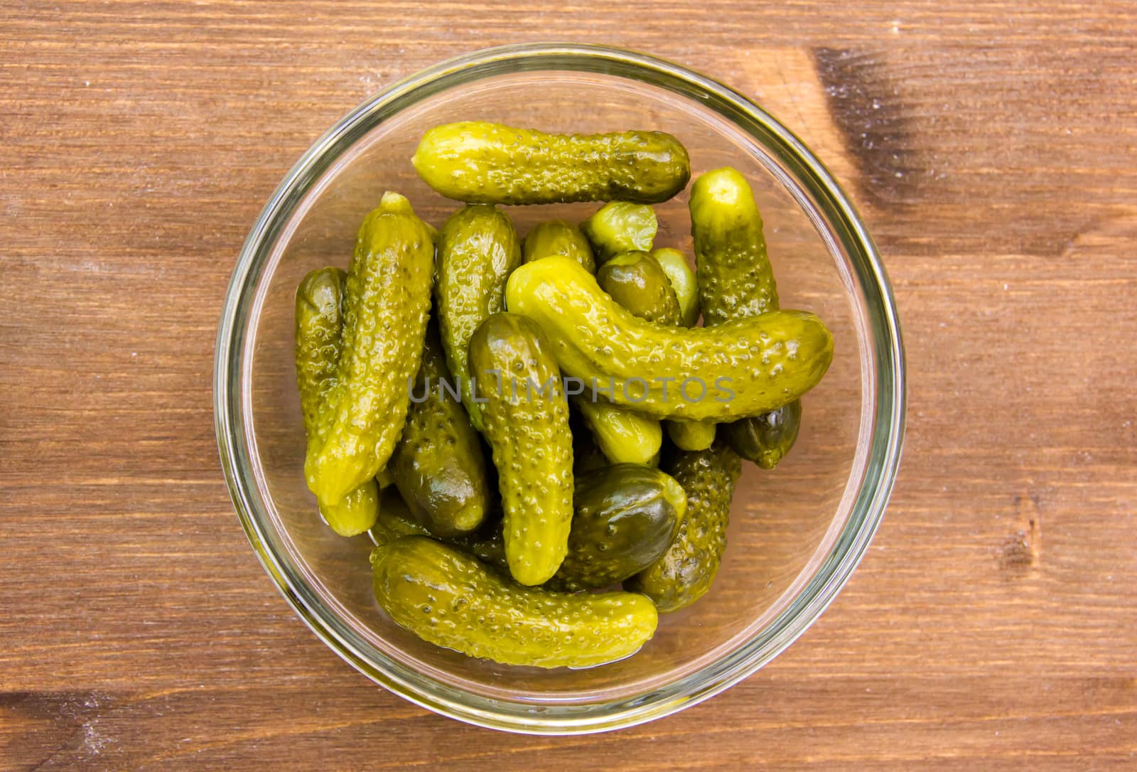 Pickles on bowl on wooden table seen from above