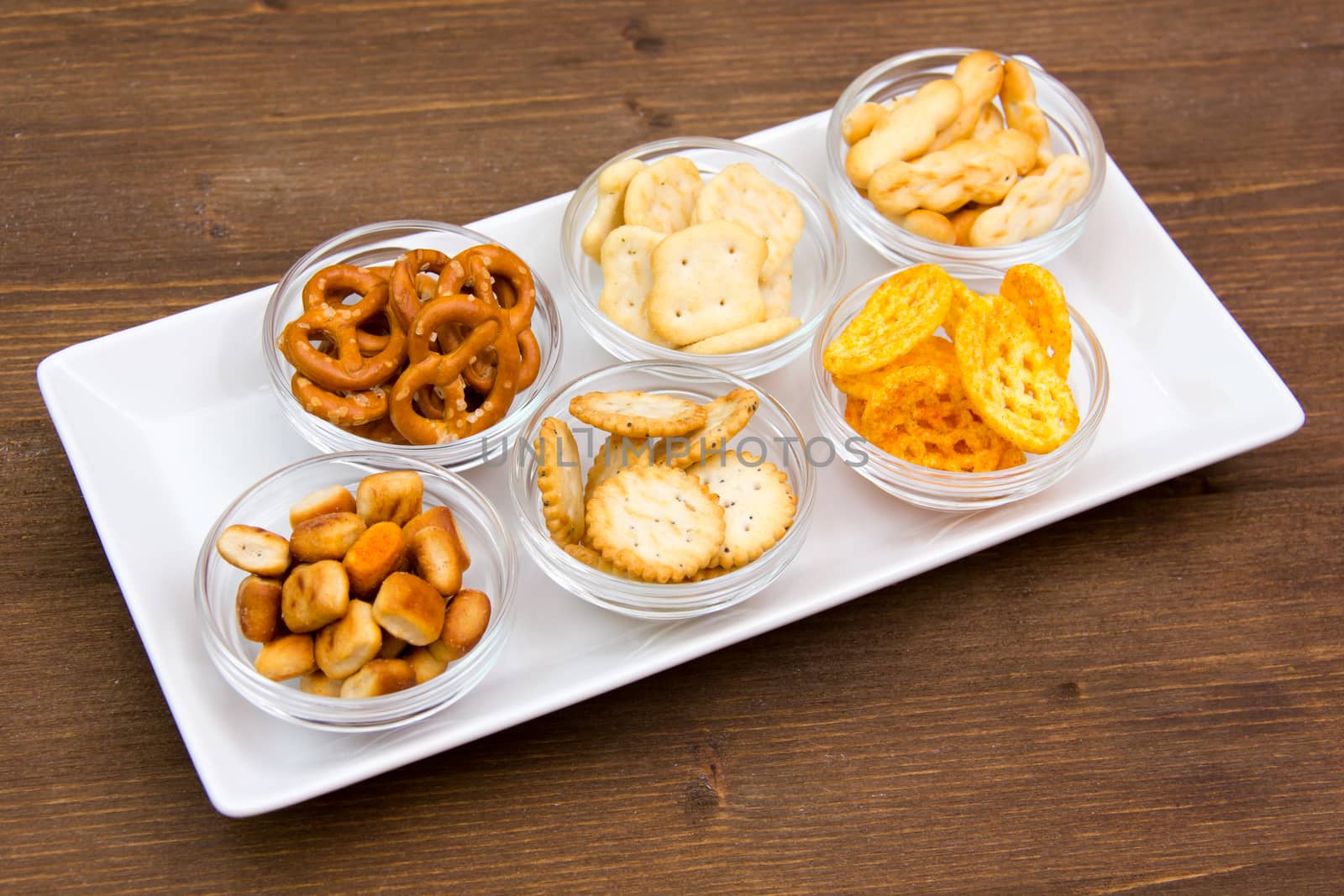 Bowls of pretzels on tray seen from above on wooden table