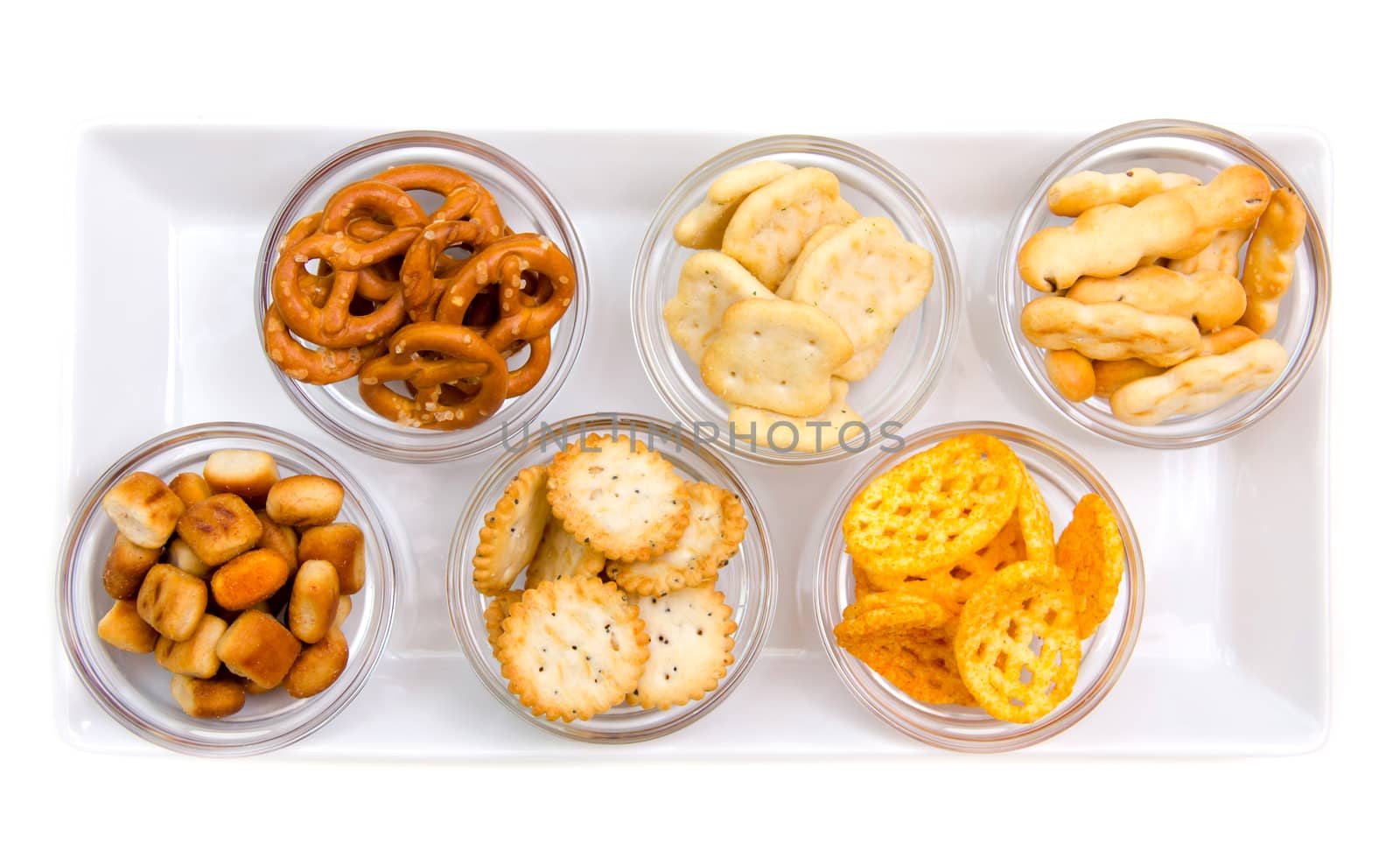 Pretzels in bowls on tray on white background seen from above