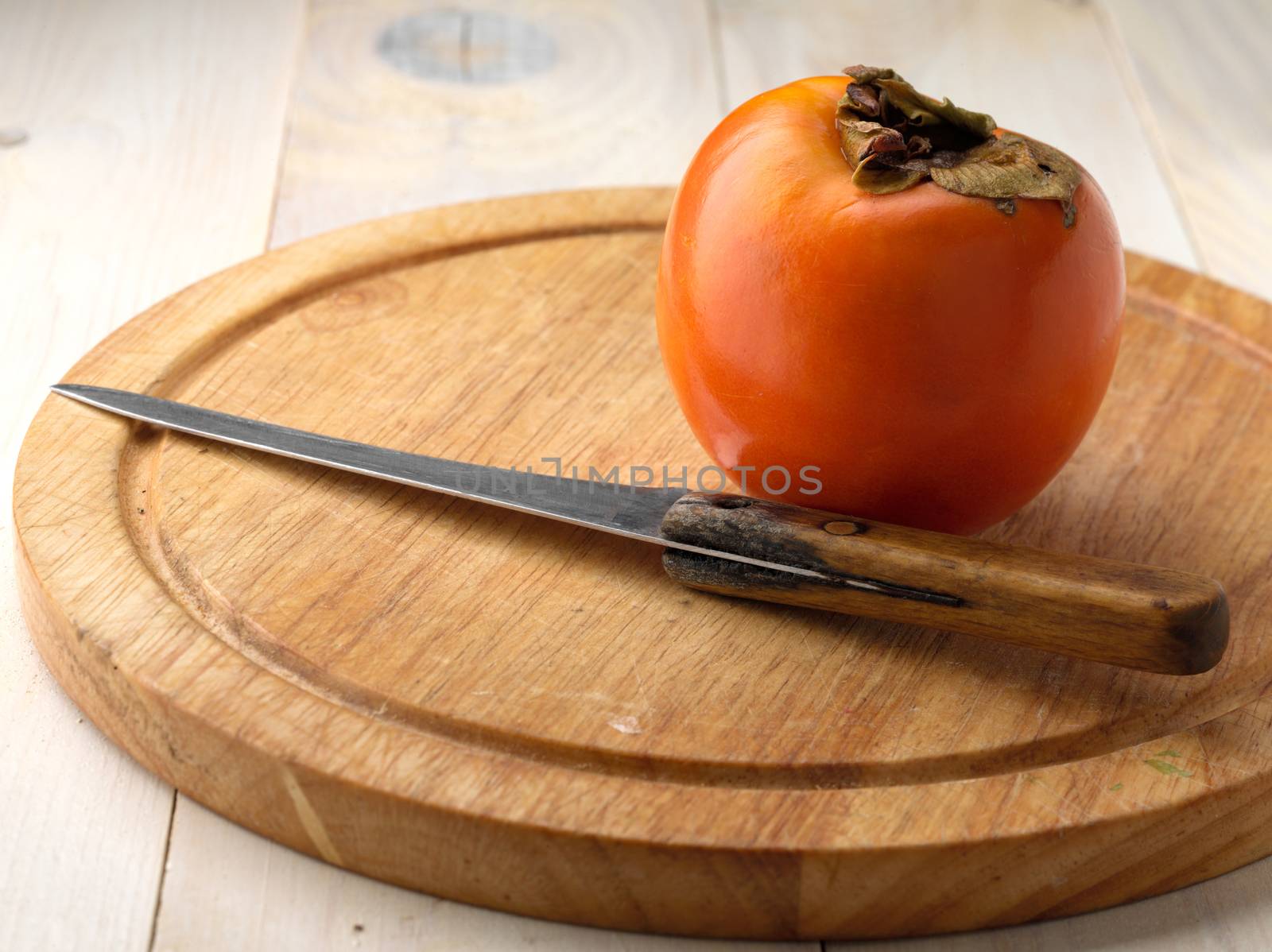 Tasty and ripe persimmon on wooden board
