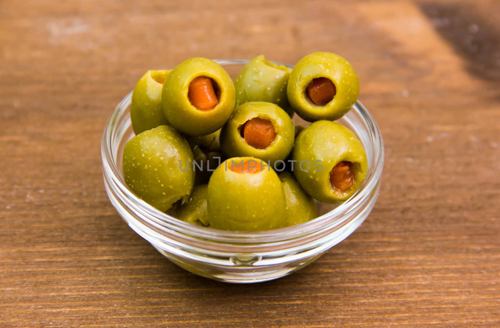 Stuffed olives in bowl on wooden table