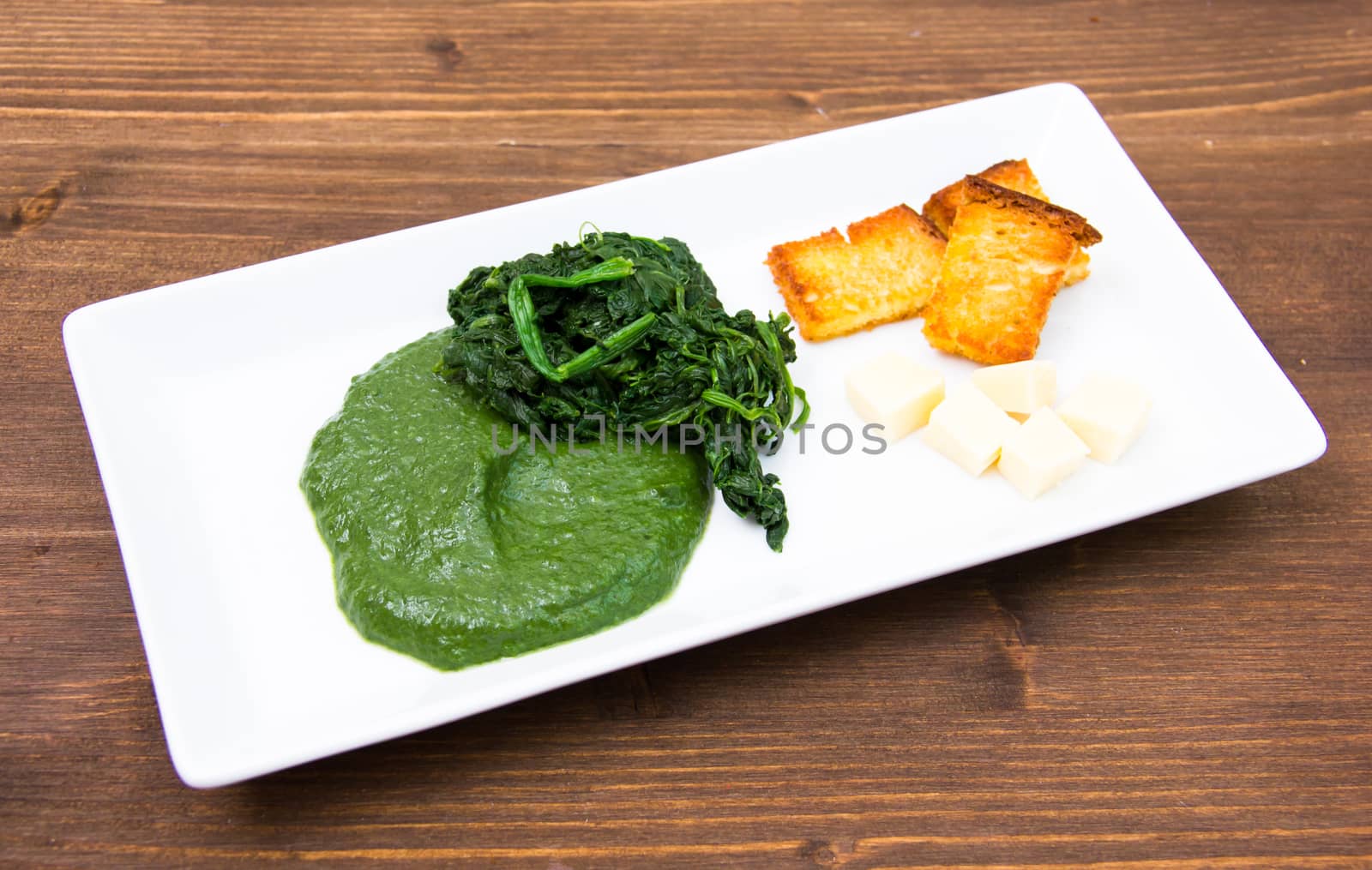 Tray with creamed spinach and croutons on wooden table
