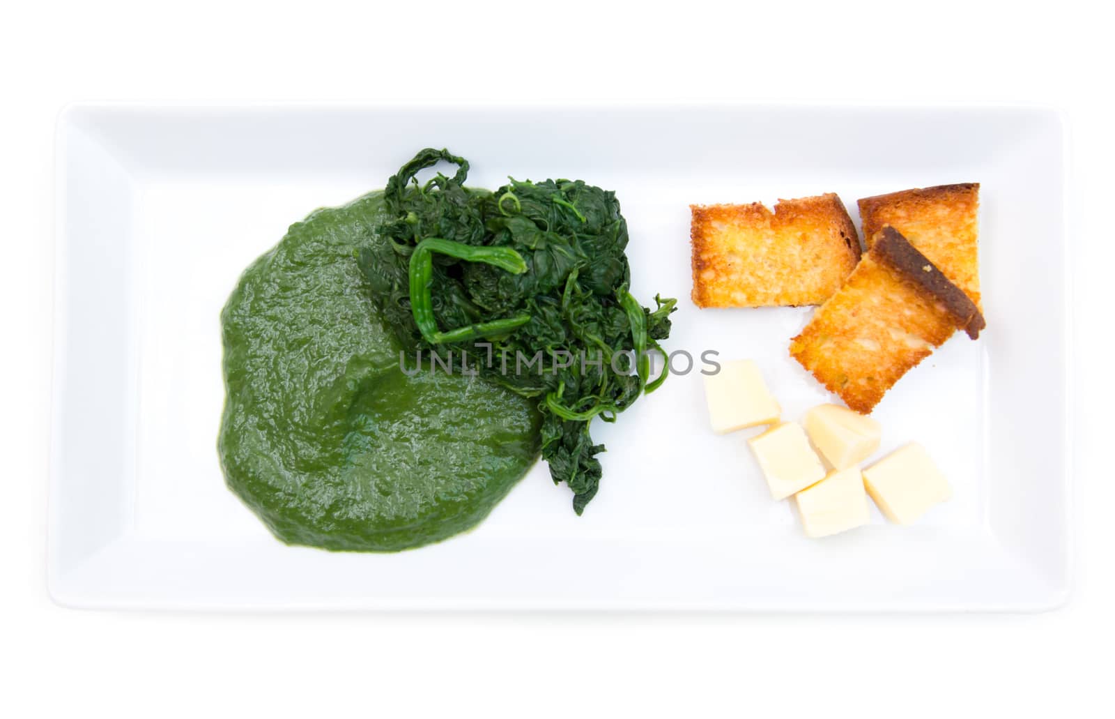 Tray with creamed spinach and croutons on a white background seen from above