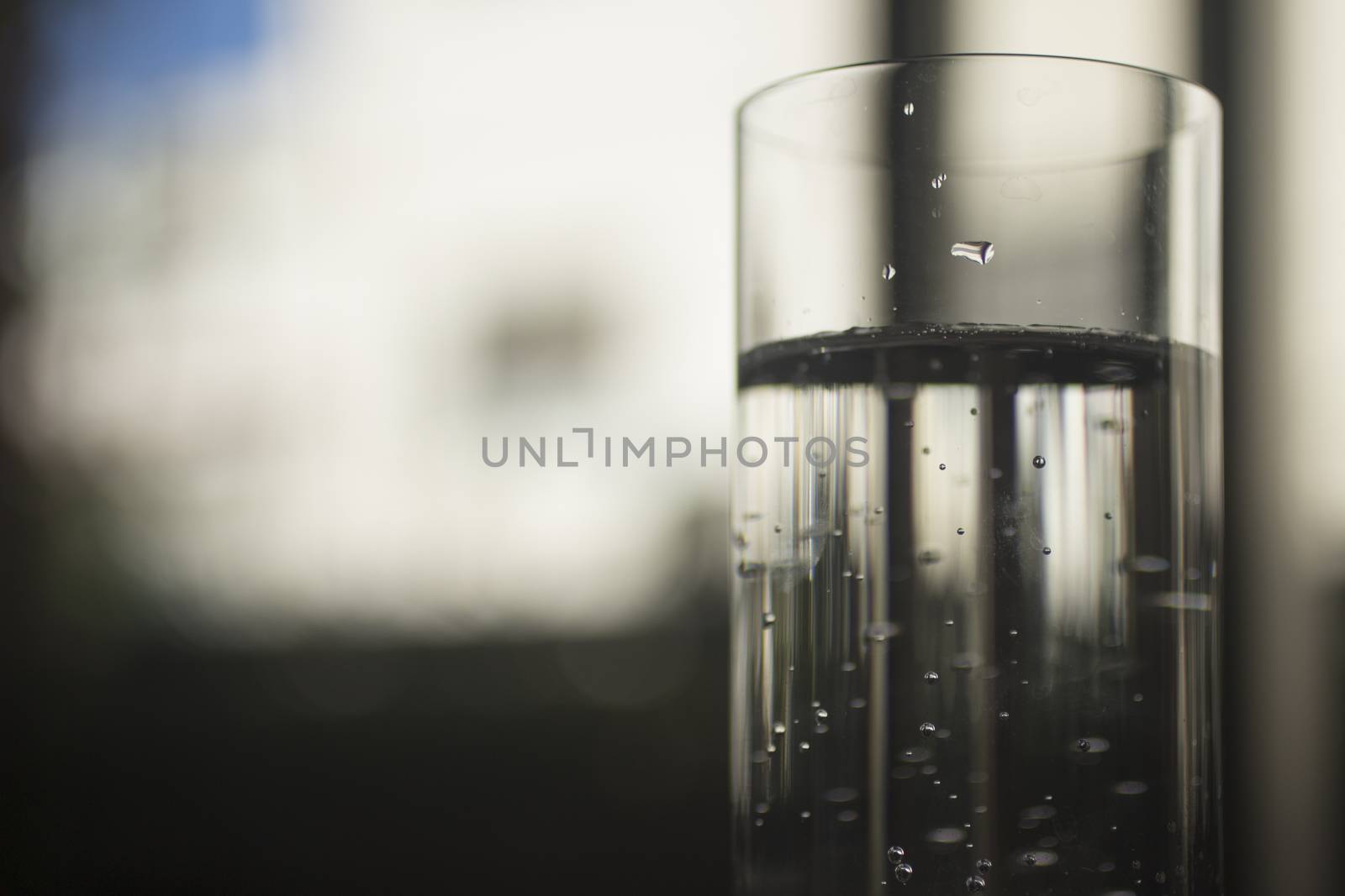 Glass of sparkling water soft drink closeup on carbon dioxide gas bubbles.