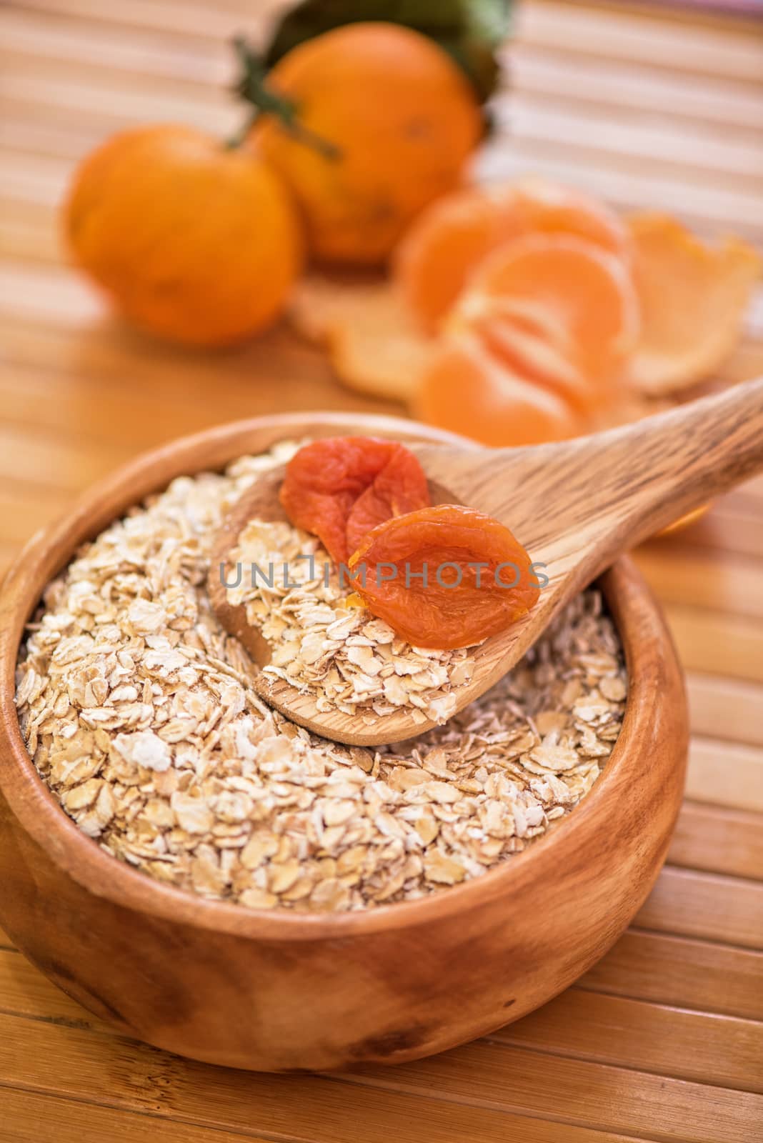 Oat flakes with  dried apricots at wooden plate on wooden background