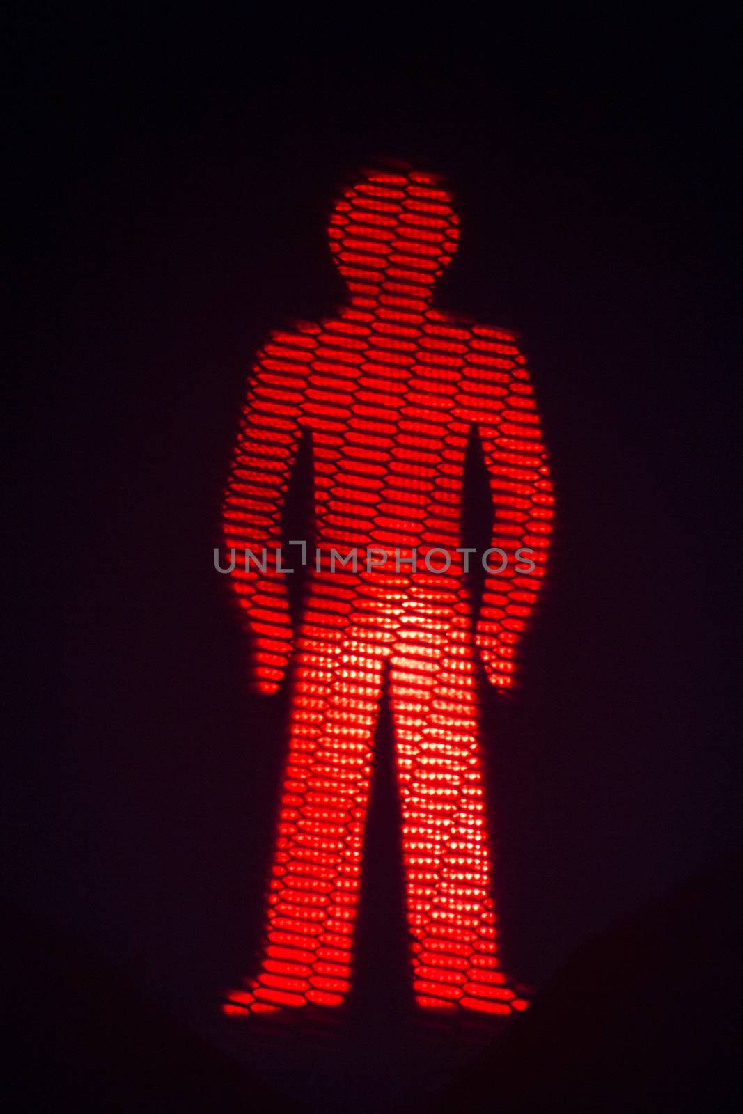 Red man pedestrian stop traffic light photo at night on black background.