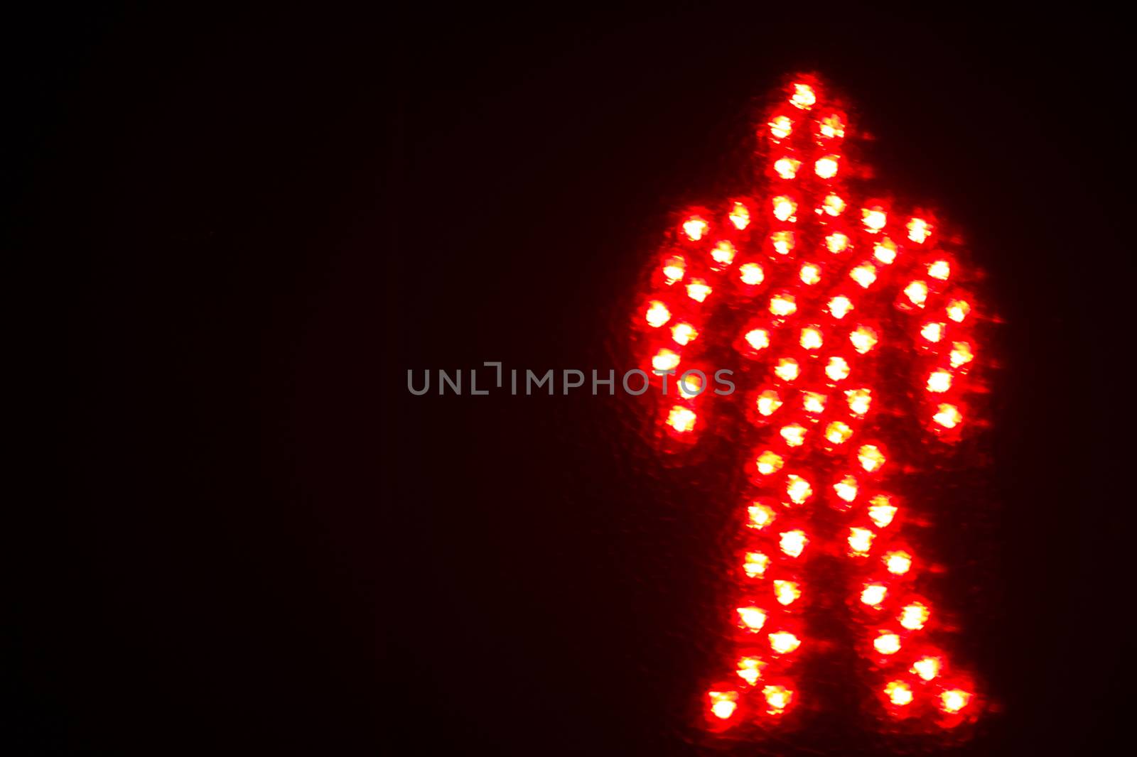 Red man pedestrian stop traffic light photo at night on black background.