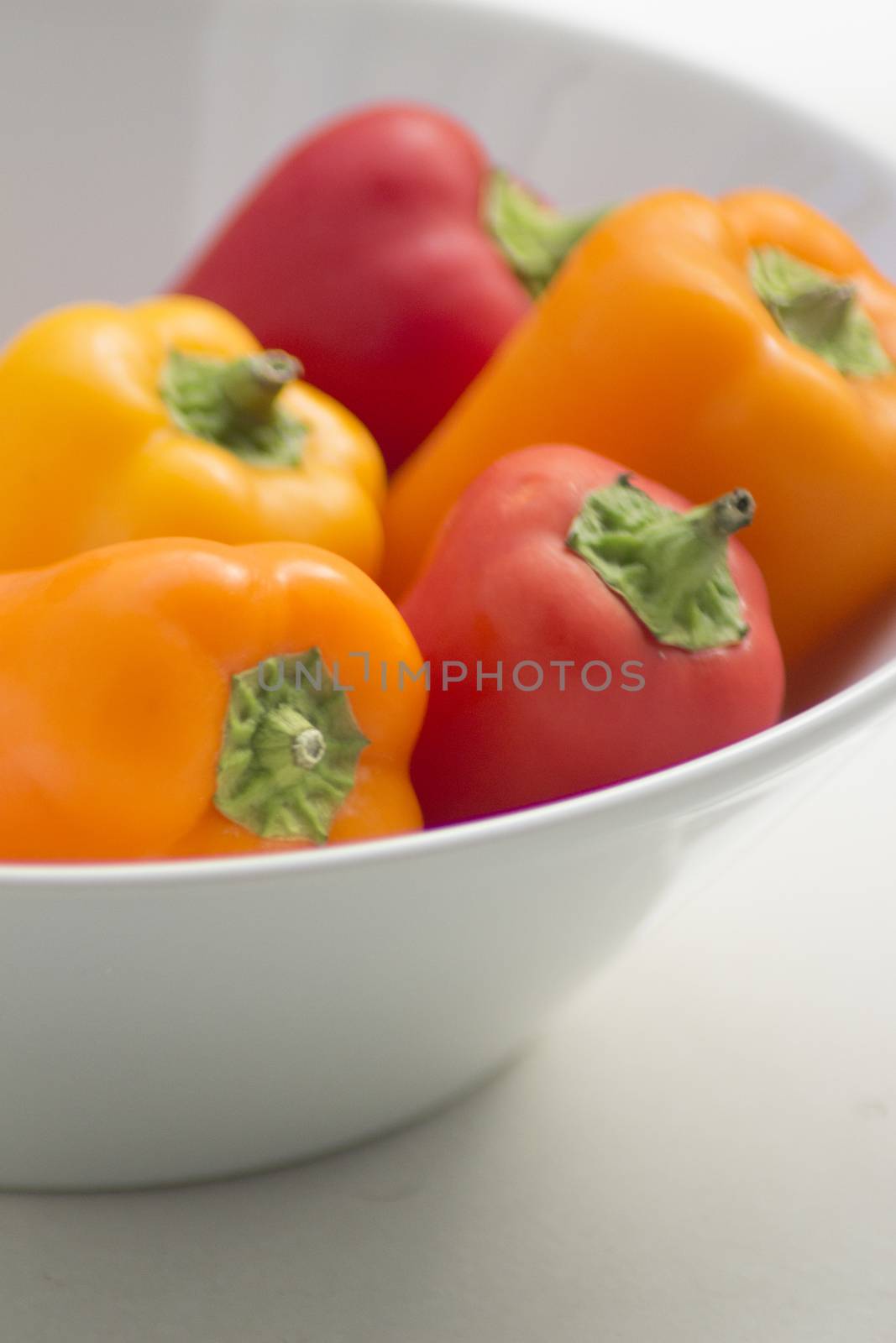 Fresh raw peppers in dish on table in sunlight in summer.