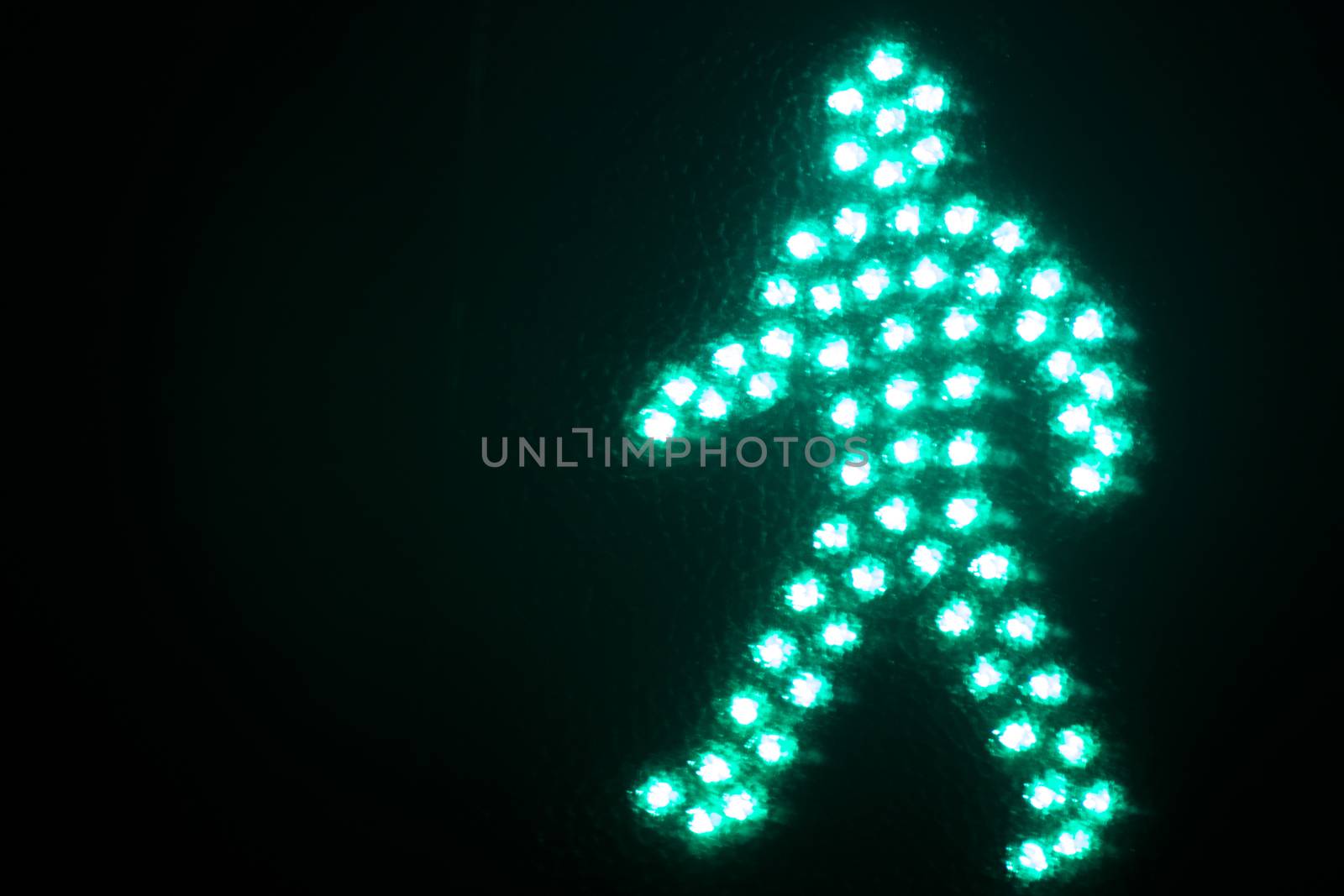 Green man go pedestrian traffic light photo at night on black background.