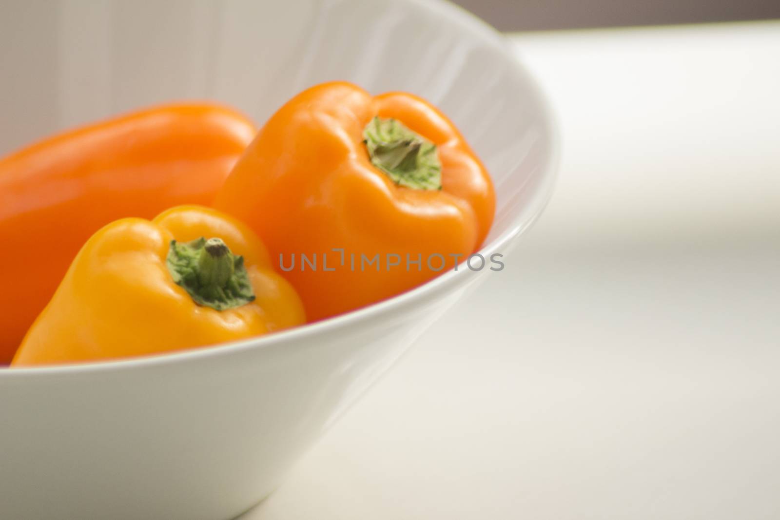 Fresh raw peppers in dish on table in sunlight in summer.