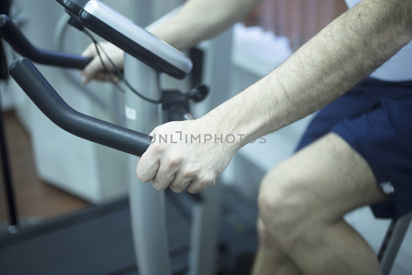 Young man on exercise bicycle in physiotherapy gym fitness center clinic.