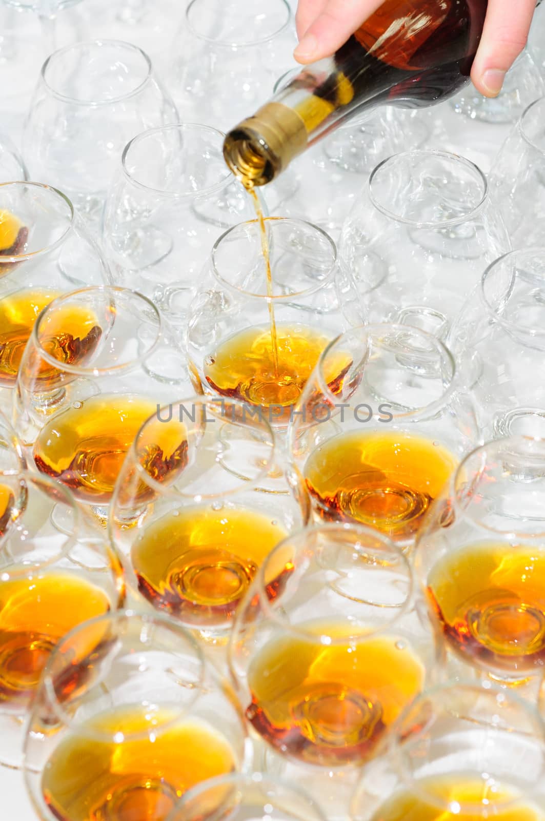 pouring the brandy or cognac into glasses in rows