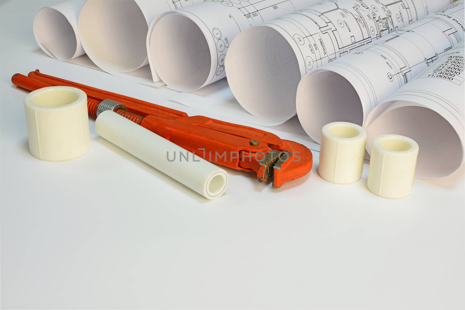 Drawing rolls, gas wrench, pipe joints on white surface