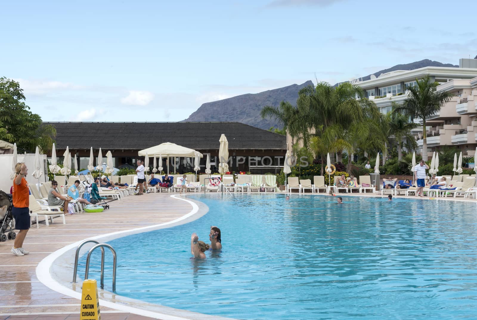 LOS CHRISTIANOS,TENERIFE-NOVEMBER 28, 2012: People enjoy vacation near the swimming pool at resort in Tenerife, on November 28,Tenerife tis one of the popular island of canadian islands.