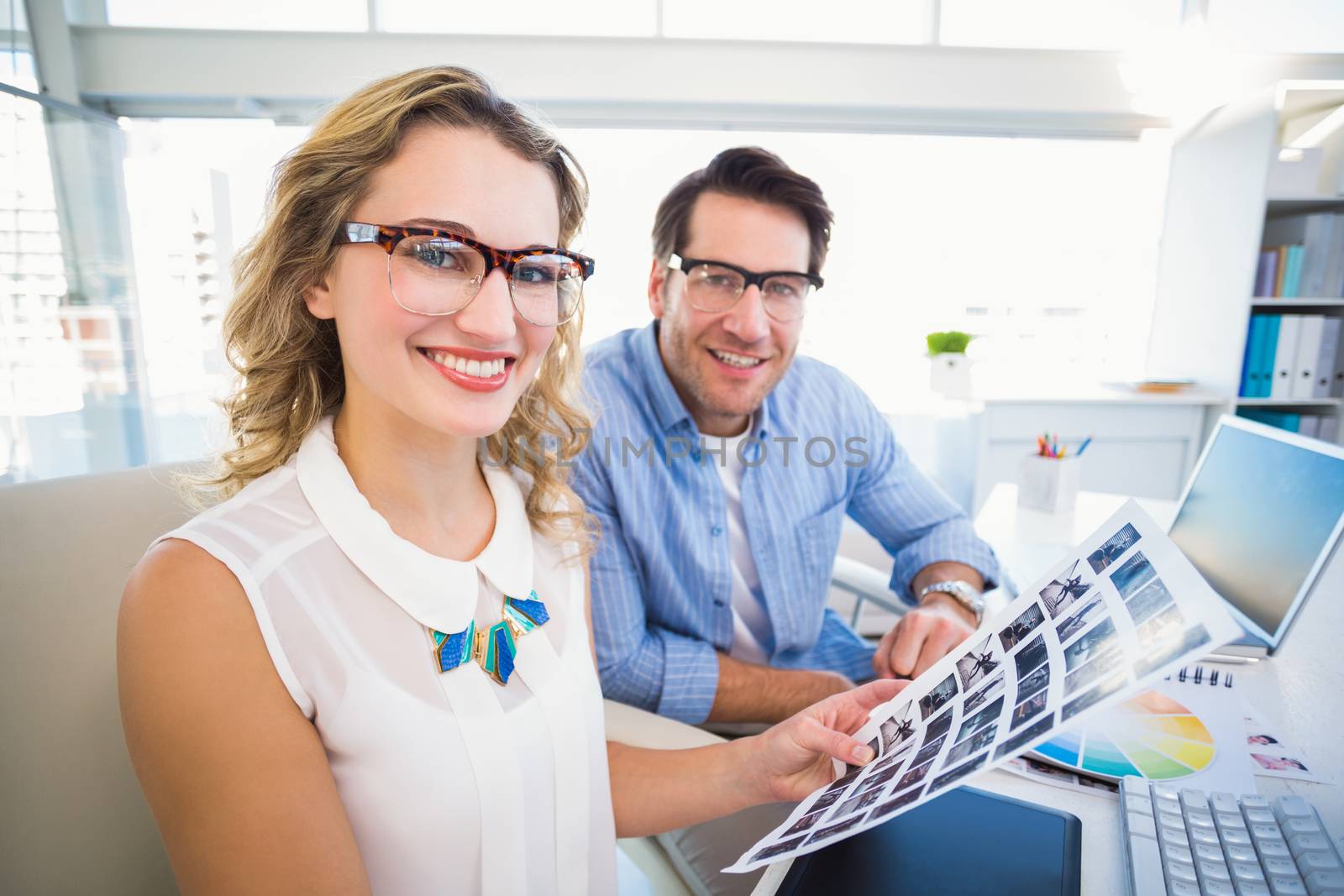 Editors working with contact sheets and looking at camera in office