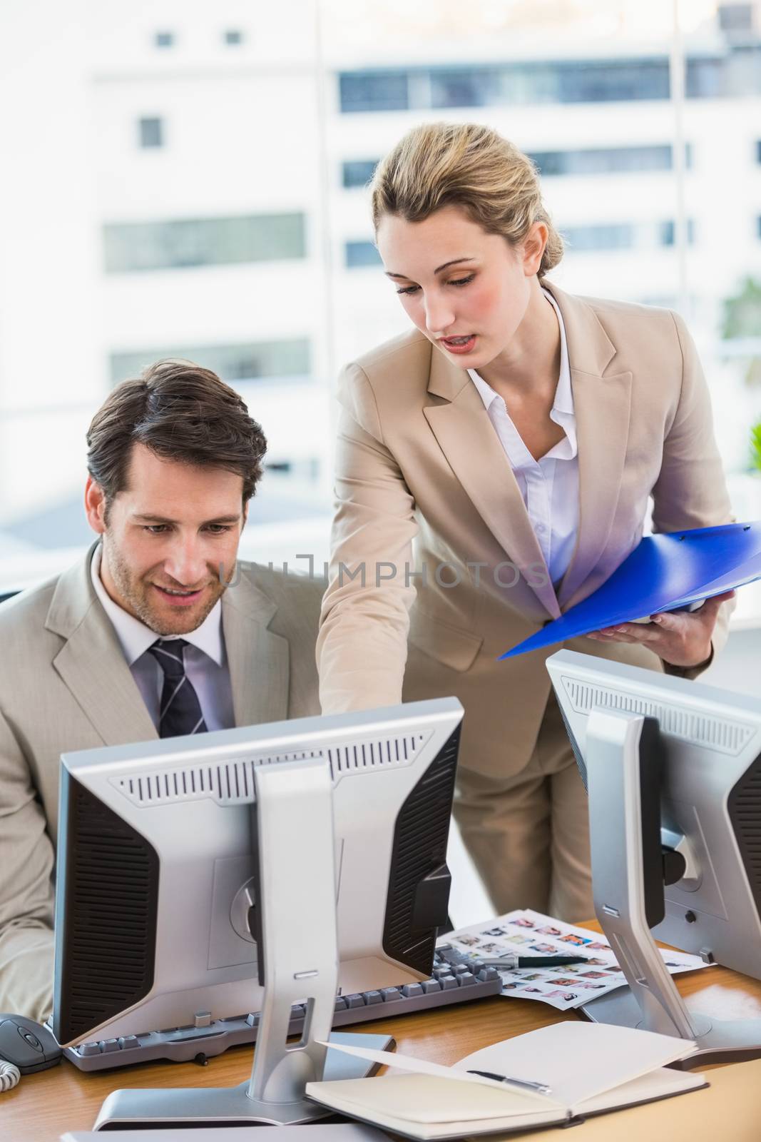 Woman showing her colleague something on the screen at work